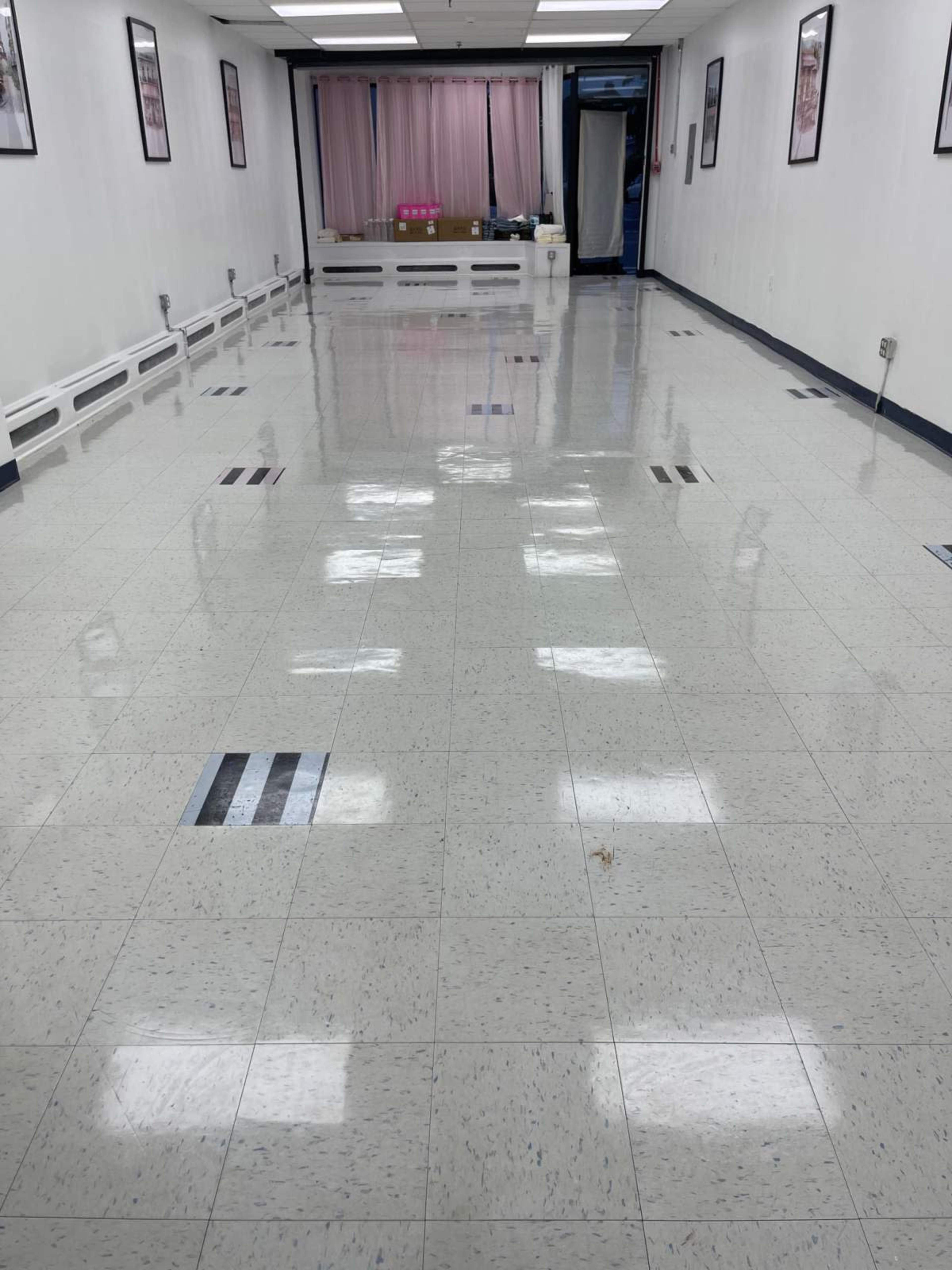 The image shows a clean, empty room with polished tile flooring and framed pictures on the walls.