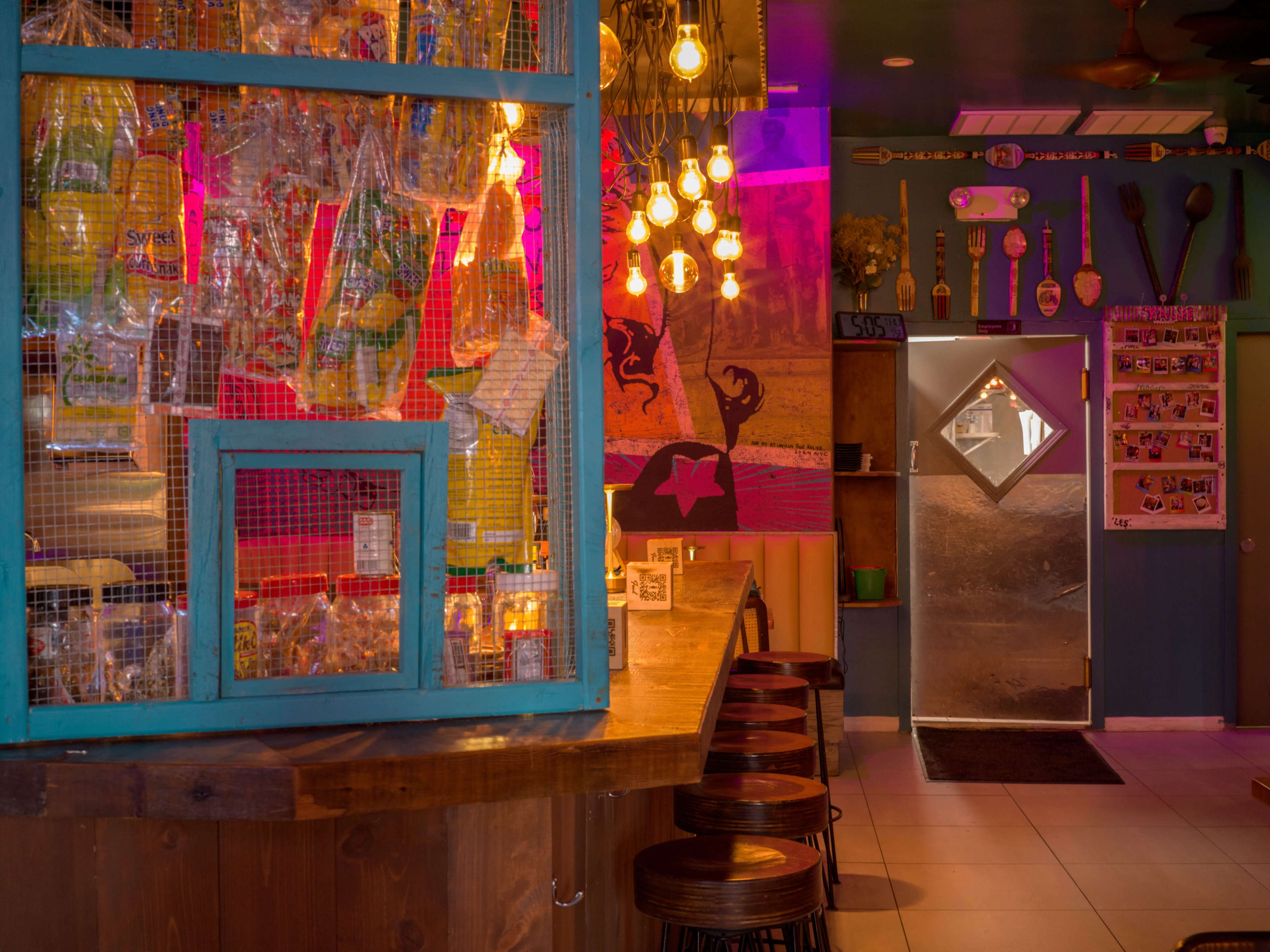 The scene features a colorful interior of a restaurant with bags of snacks displayed behind a blue counter and an illuminated door leading outside.