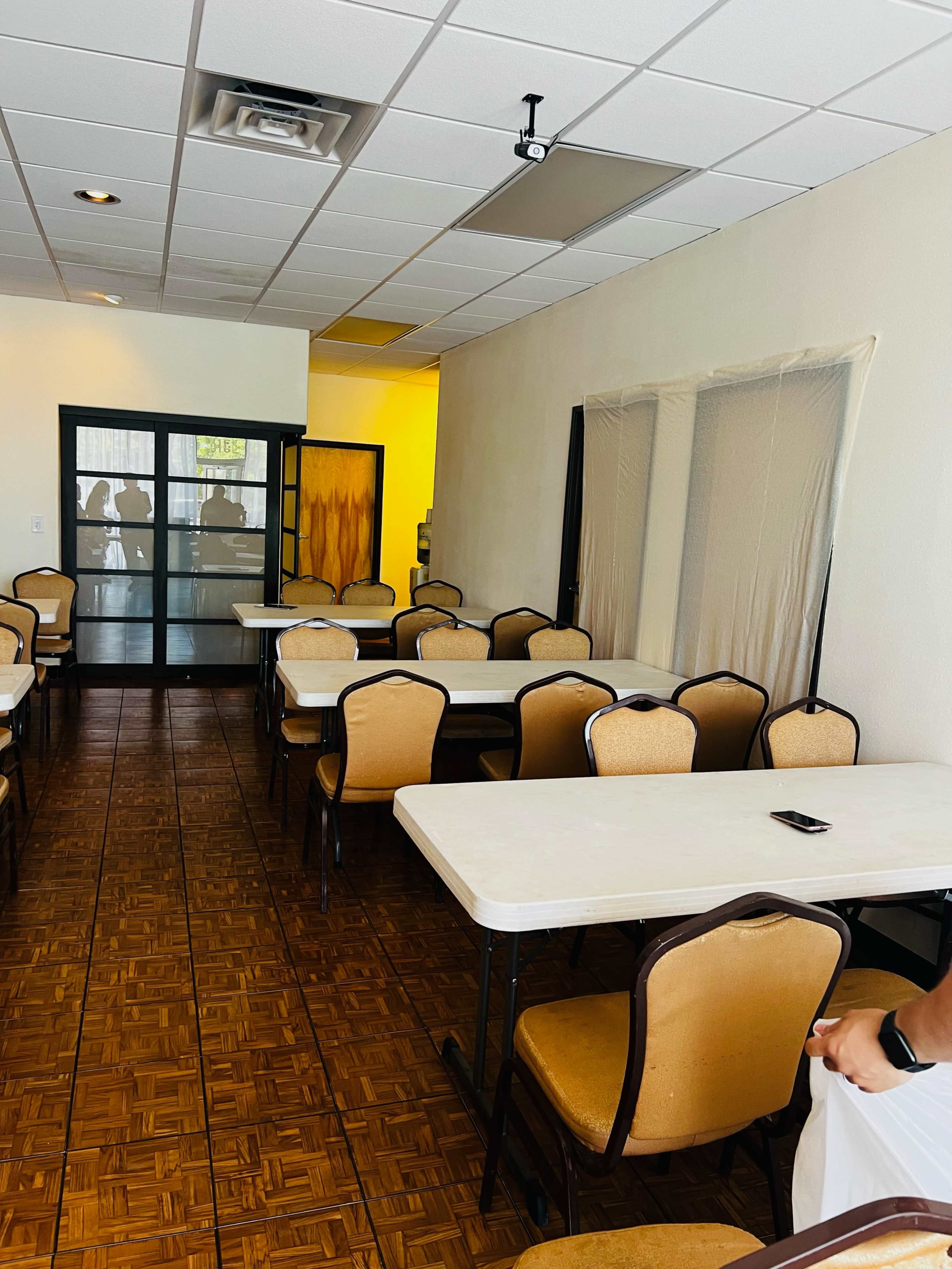 A spacious, empty dining area with several tables and chairs arranged neatly against the walls.