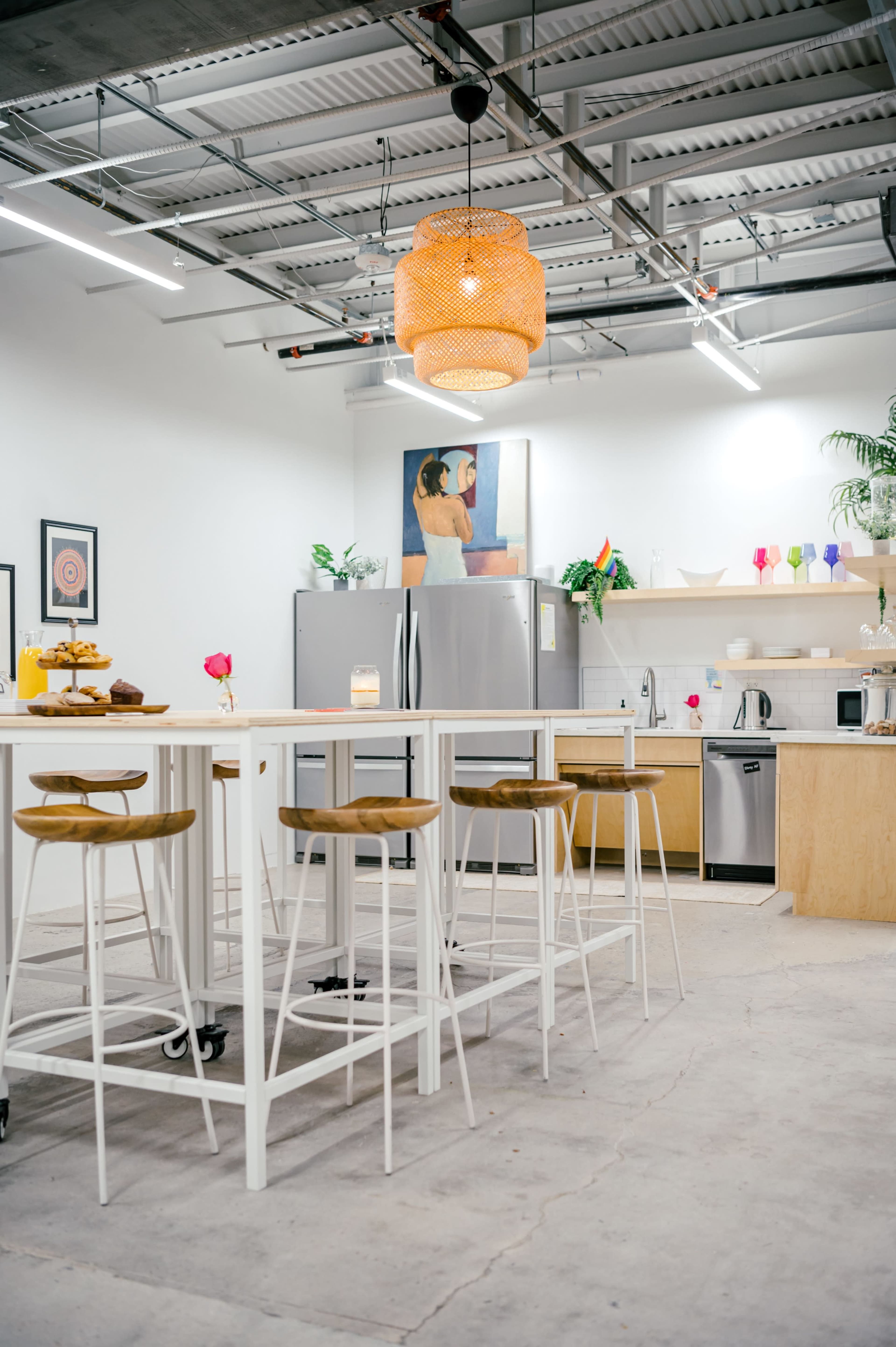 A modern kitchen with a large island and seating, stainless steel appliances, a wall-mounted artwork, and decorative plants.
