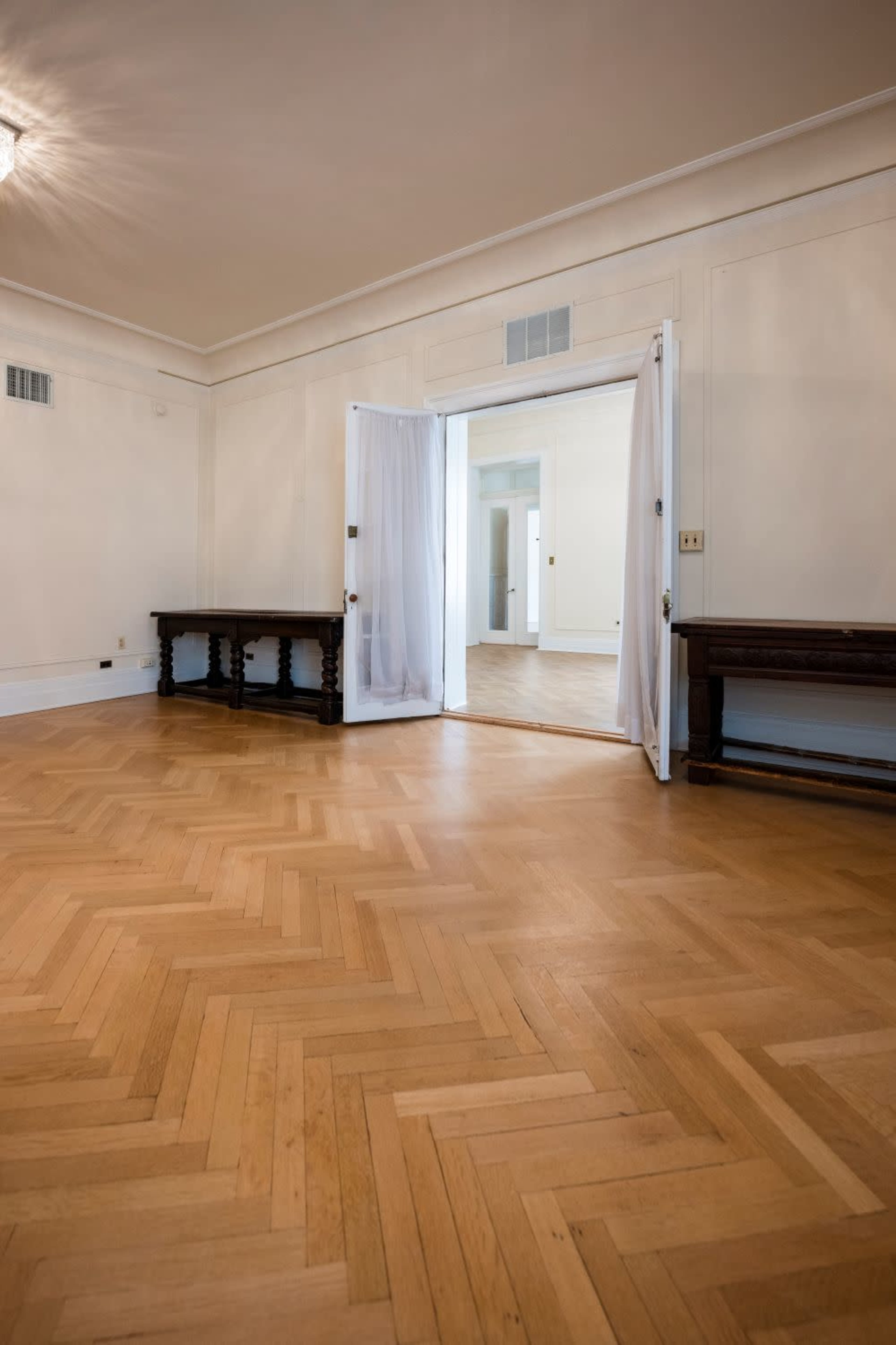 The image shows a spacious room with a polished hardwood floor and an open doorway leading to another area.