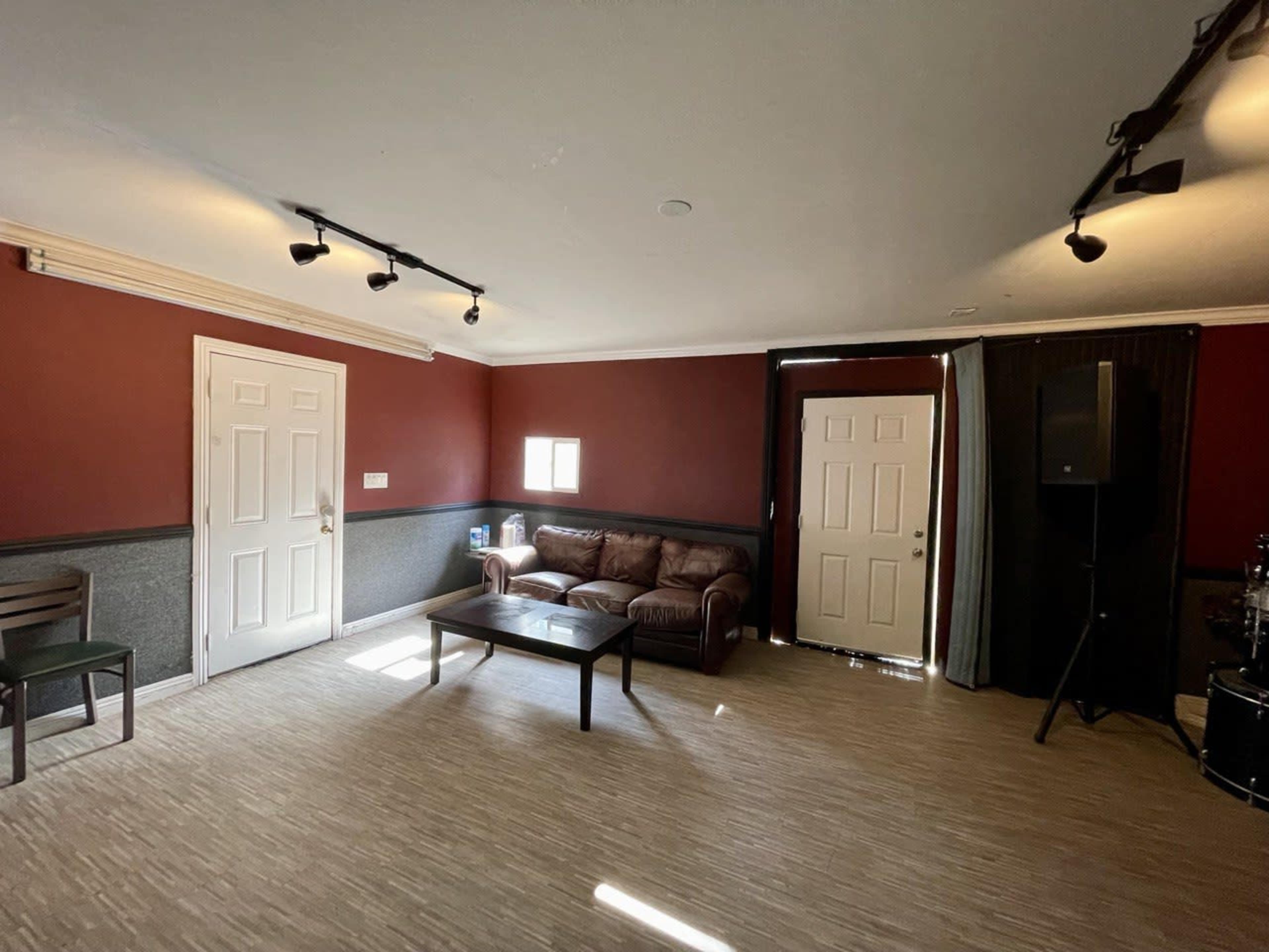 A room with red walls, a brown couch, a coffee table, and two doors, one of which is open.