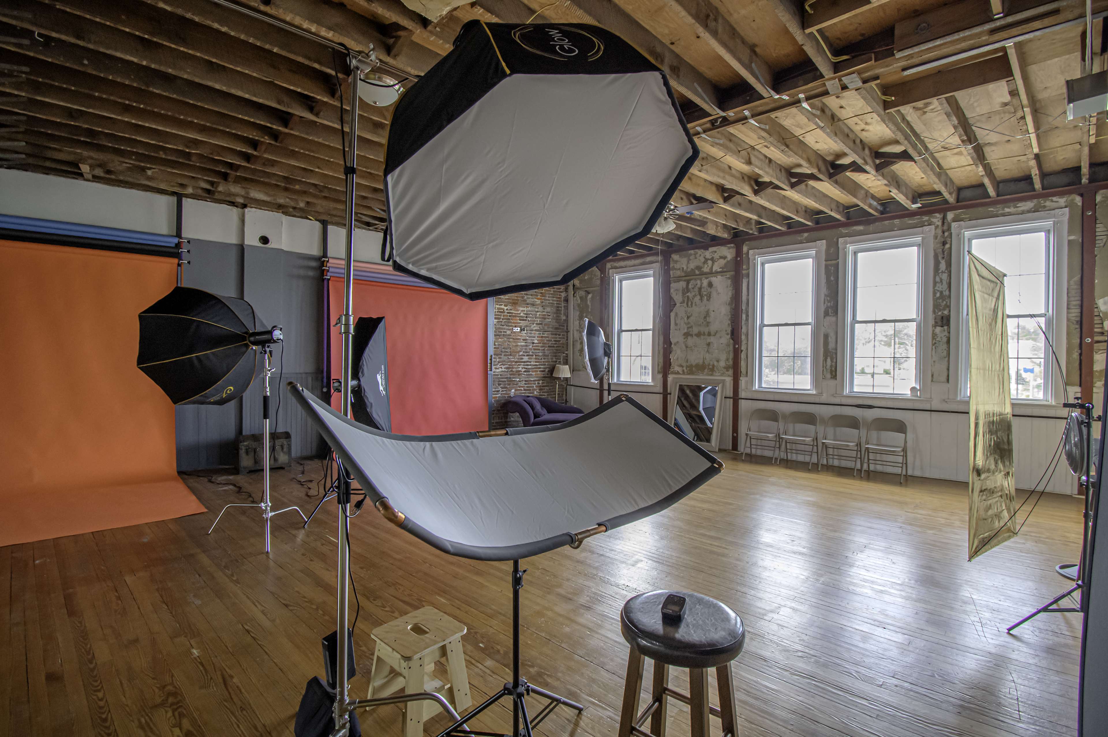 A photography studio with various lighting equipment set up, including softboxes and a backdrop.