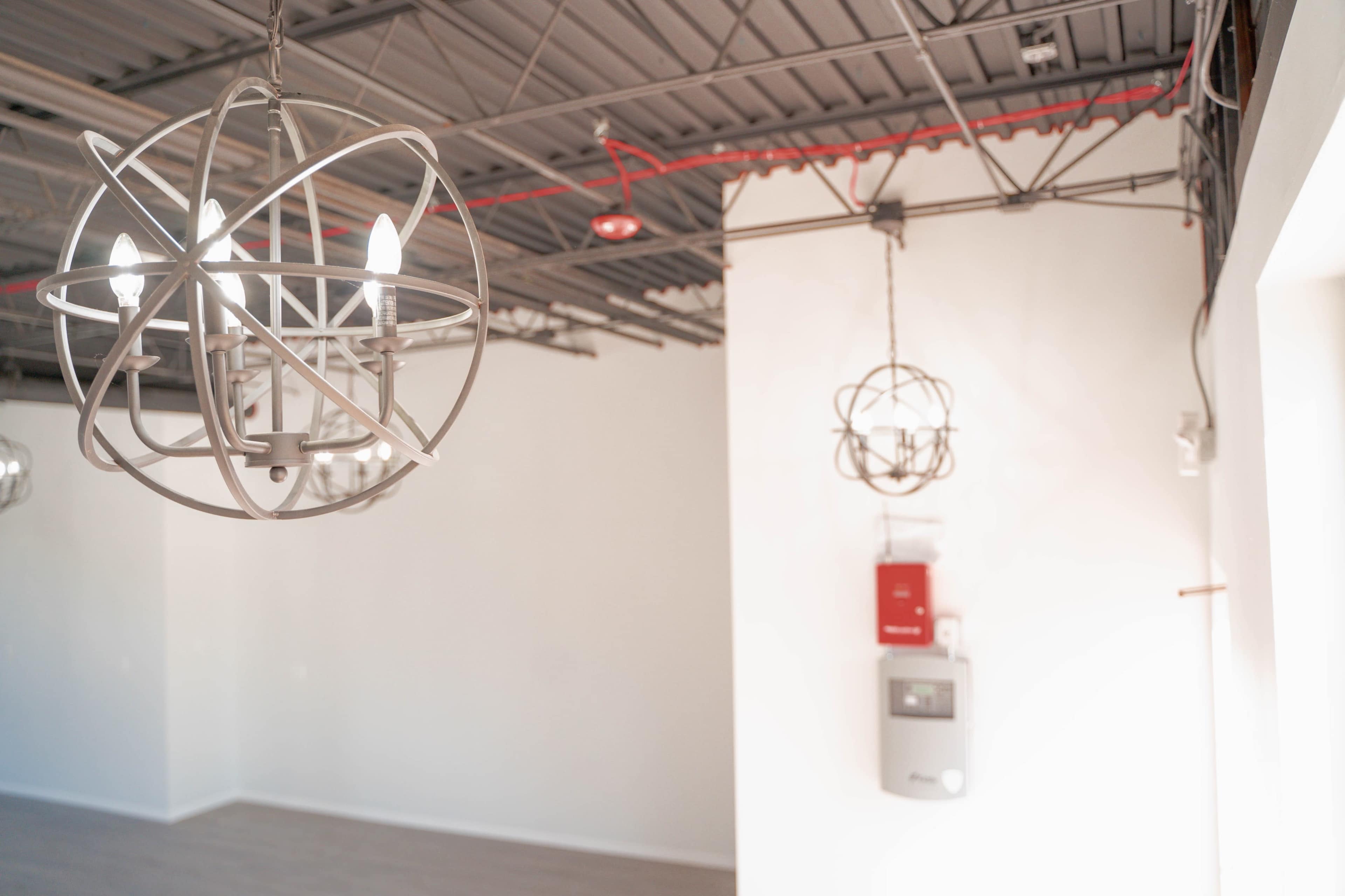 A modern interior space with two spherical light fixtures hanging from the ceiling and a wall-mounted electrical panel.