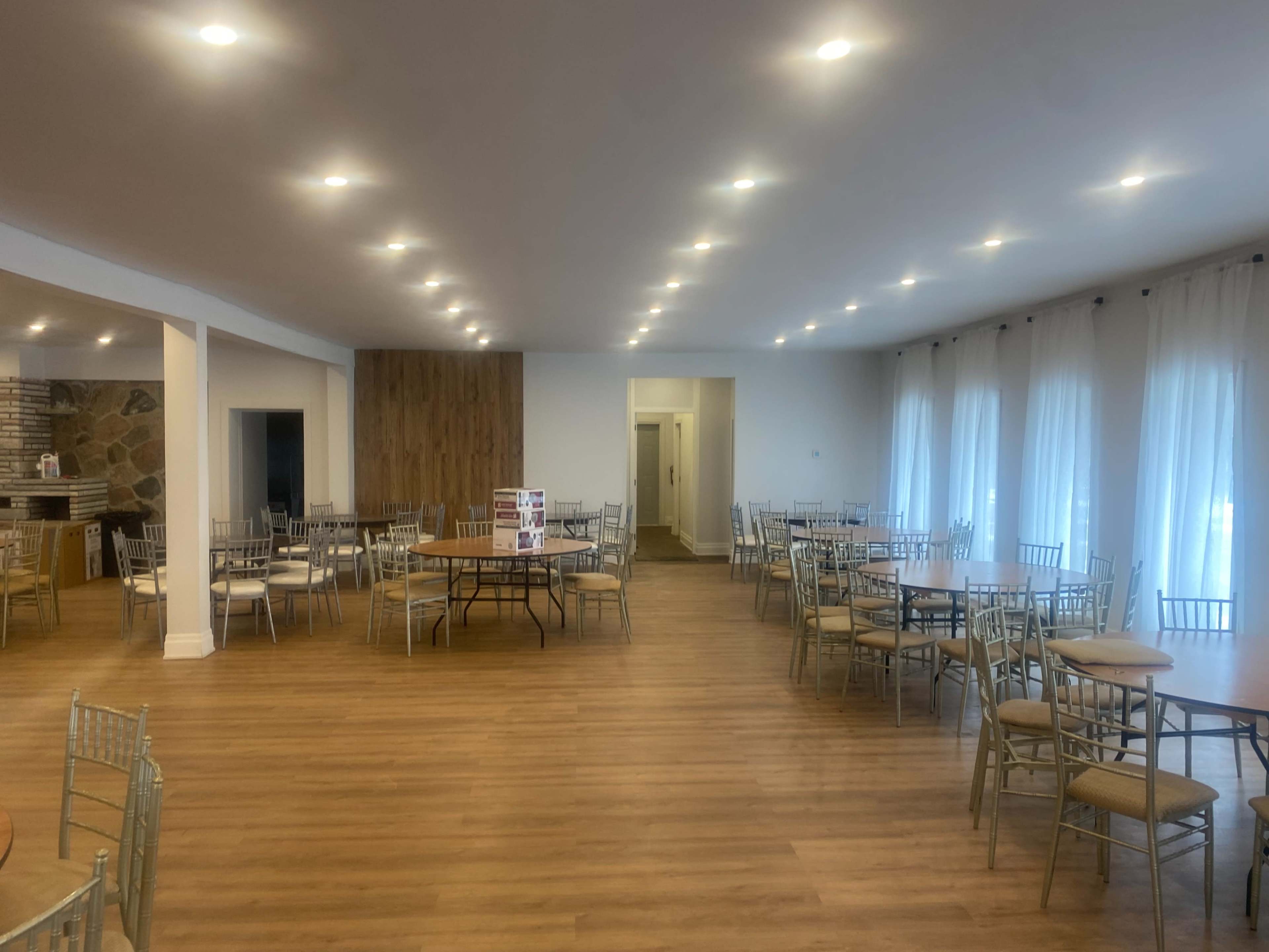 The image shows a spacious, well-lit interior of a dining area with several round tables and chairs arranged throughout the room.