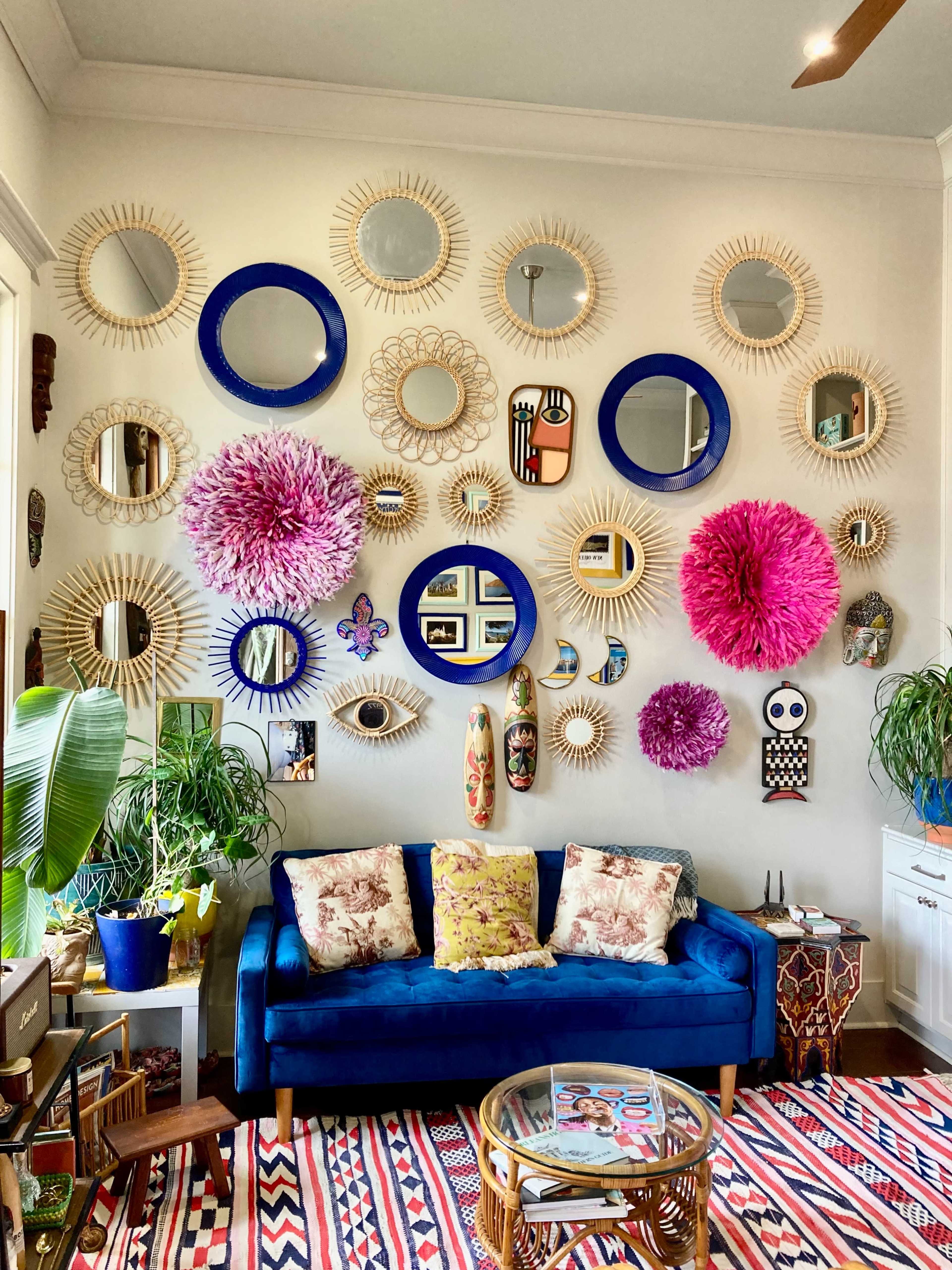 The image features a vibrant living room wall adorned with various decorative mirrors and wall art, complemented by a blue couch and a patterned rug.