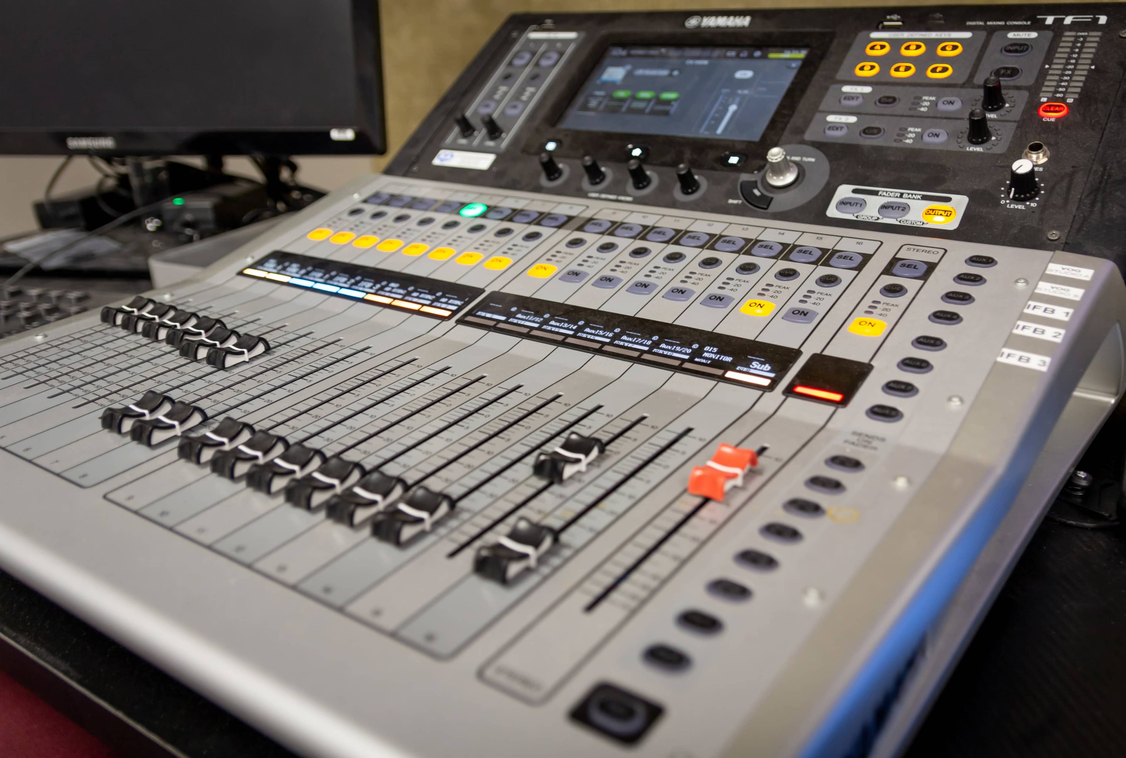 A Yamaha TF1 digital mixer with various faders, buttons, and a digital display.