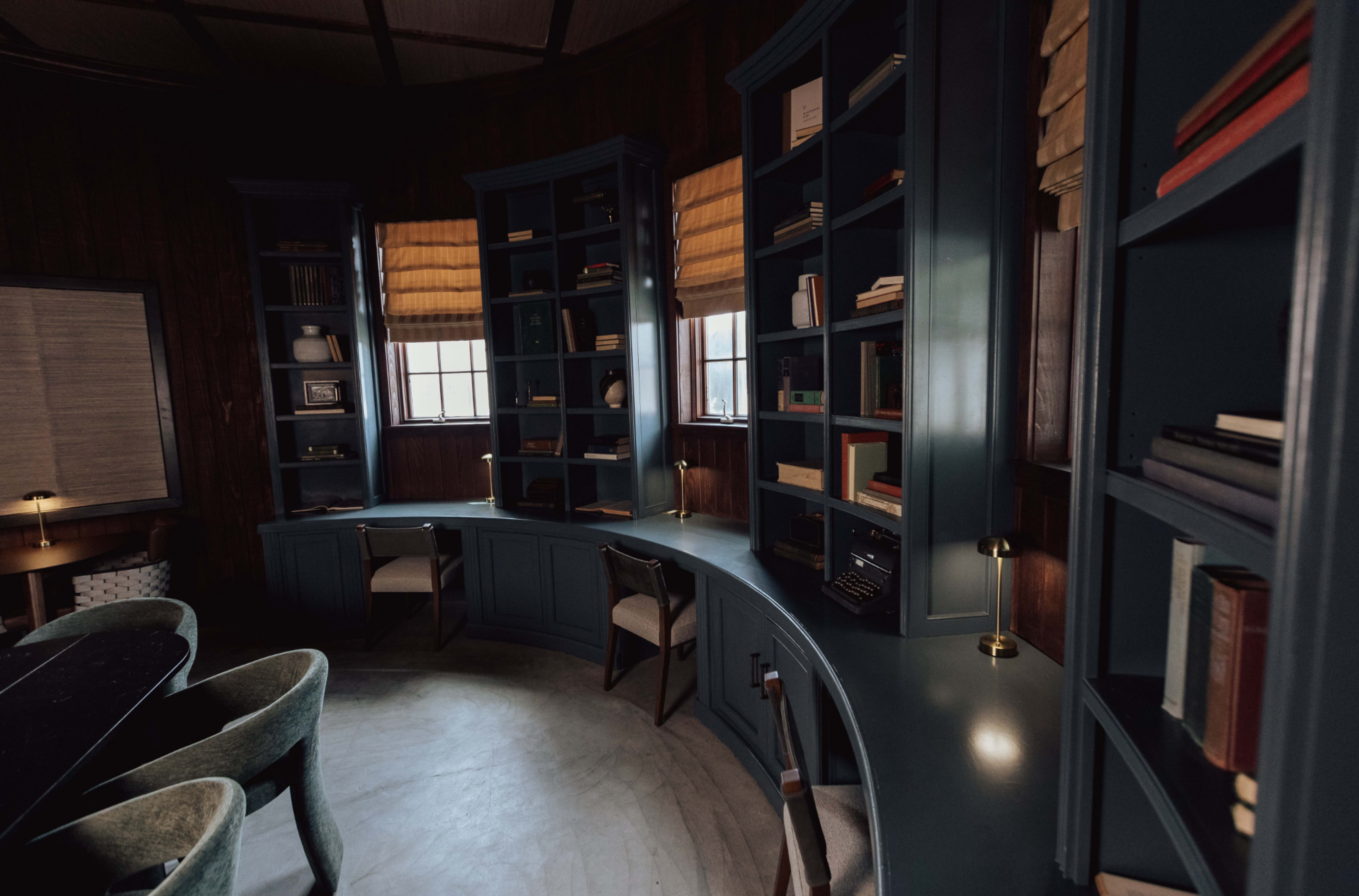 A curved desk and bookshelves filled with books in a dimly lit, circular room.