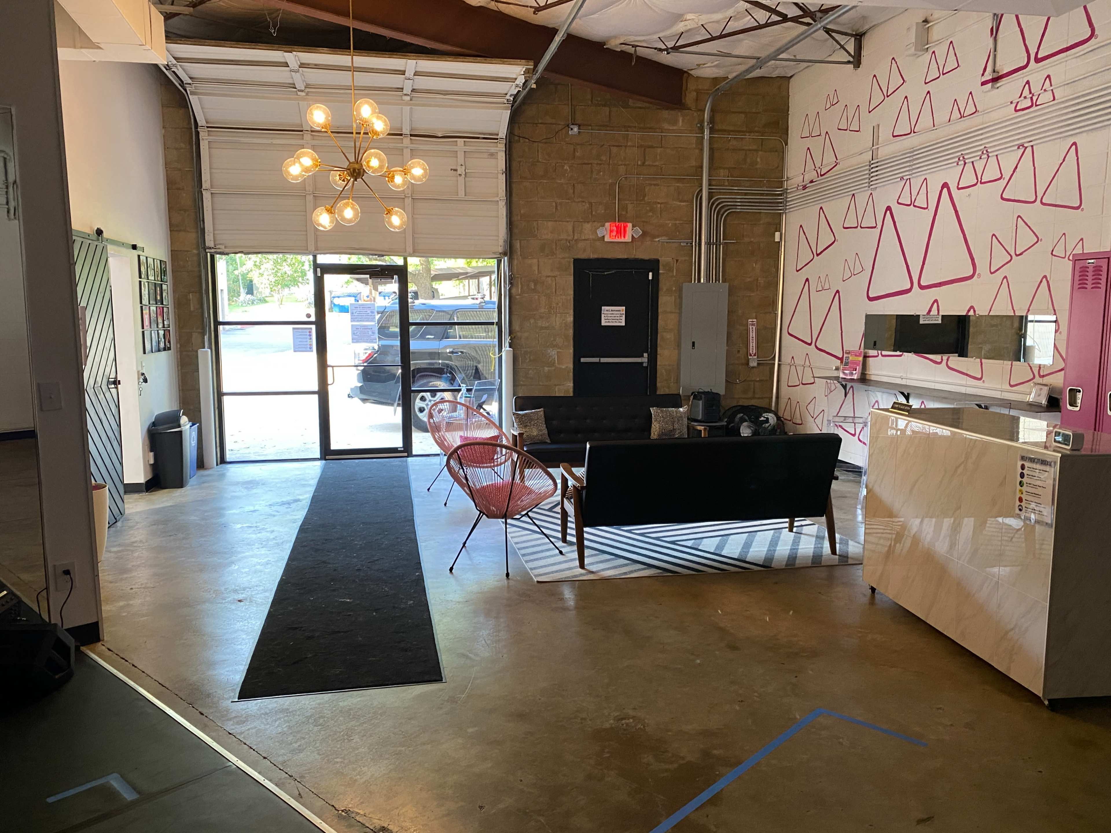 A modern interior space with a seating area, a reception desk, and large doors leading outside.