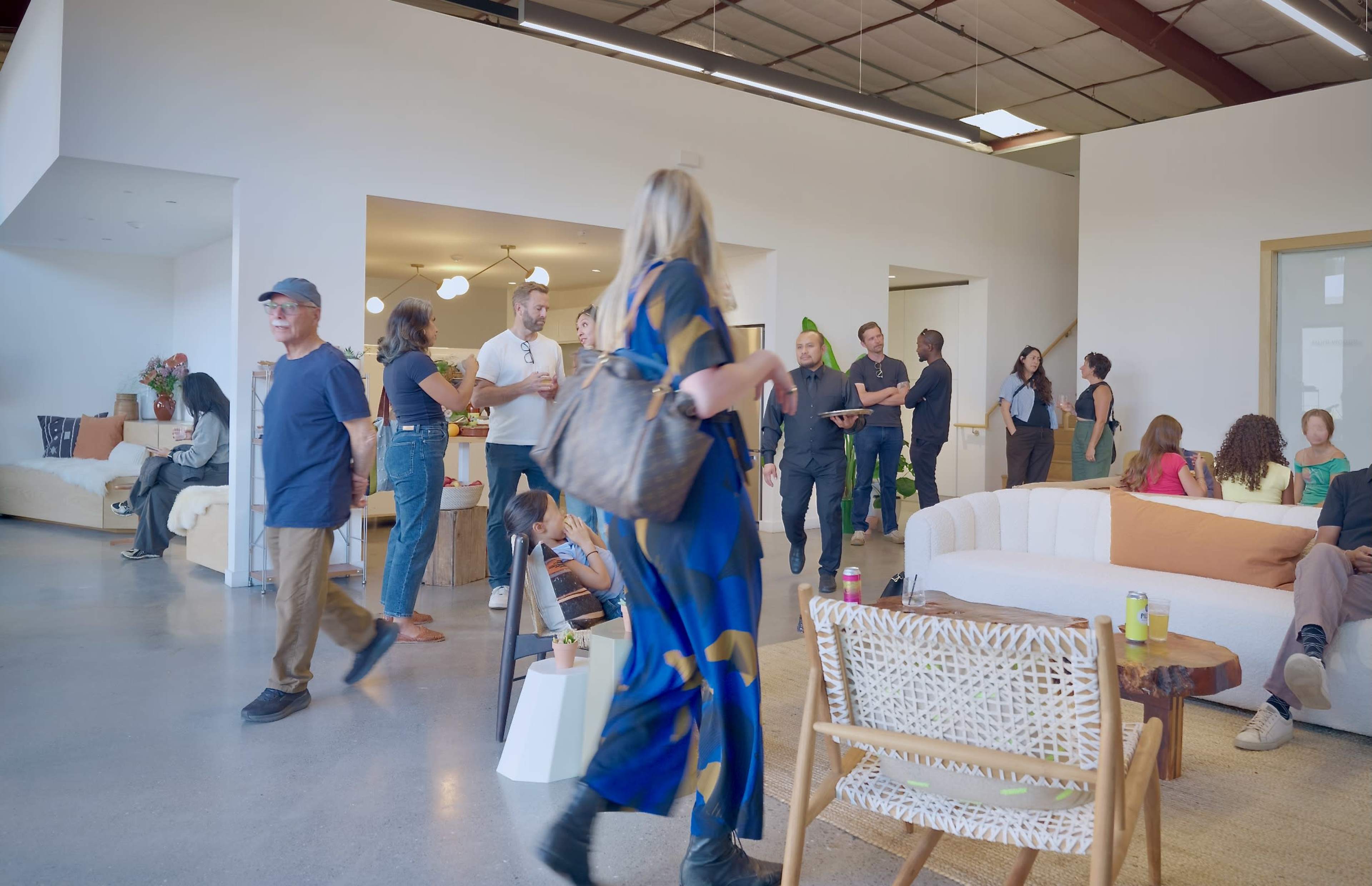 A diverse group of people is mingling in a spacious, modern interior designed for social gatherings.
