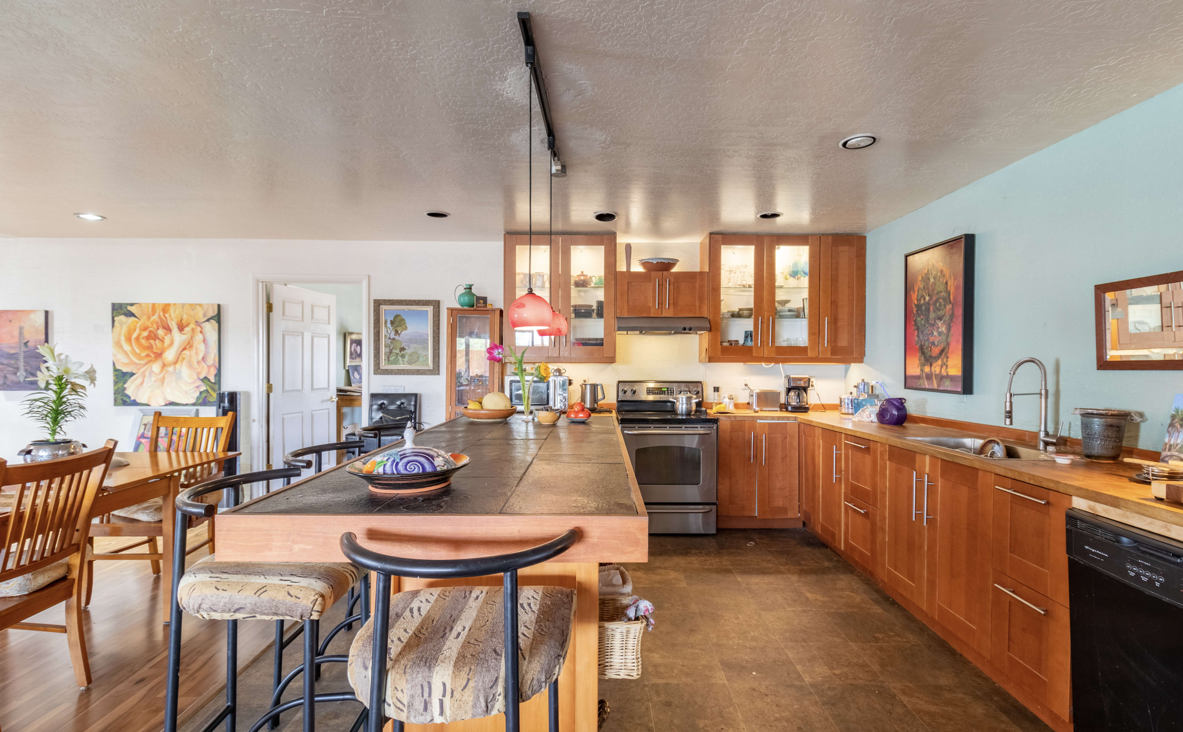 A modern kitchen with wooden cabinetry, a central island with bar stools, and various appliances.