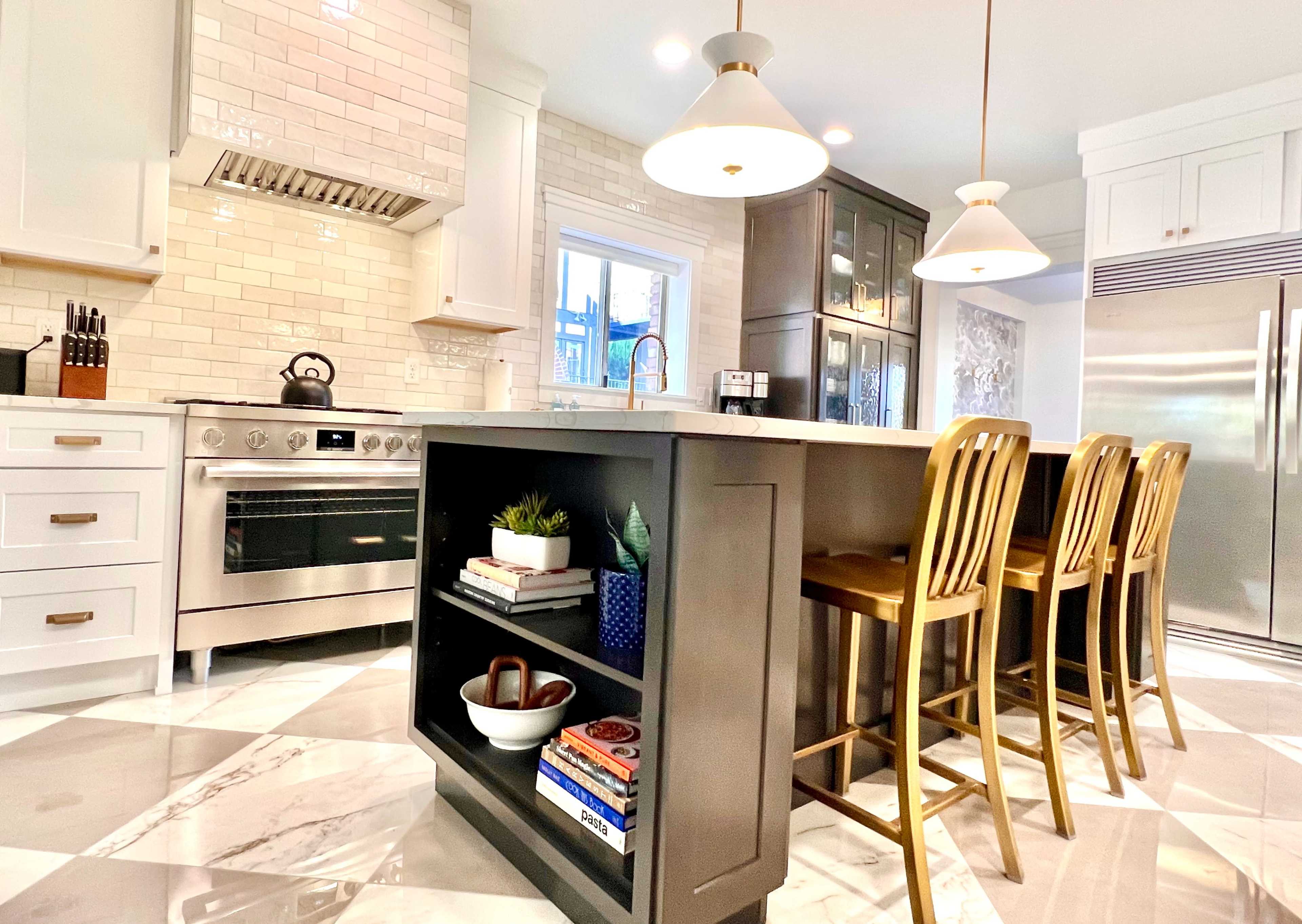 A modern kitchen features a central island with bar seating, stainless steel appliances, and light-colored cabinetry.