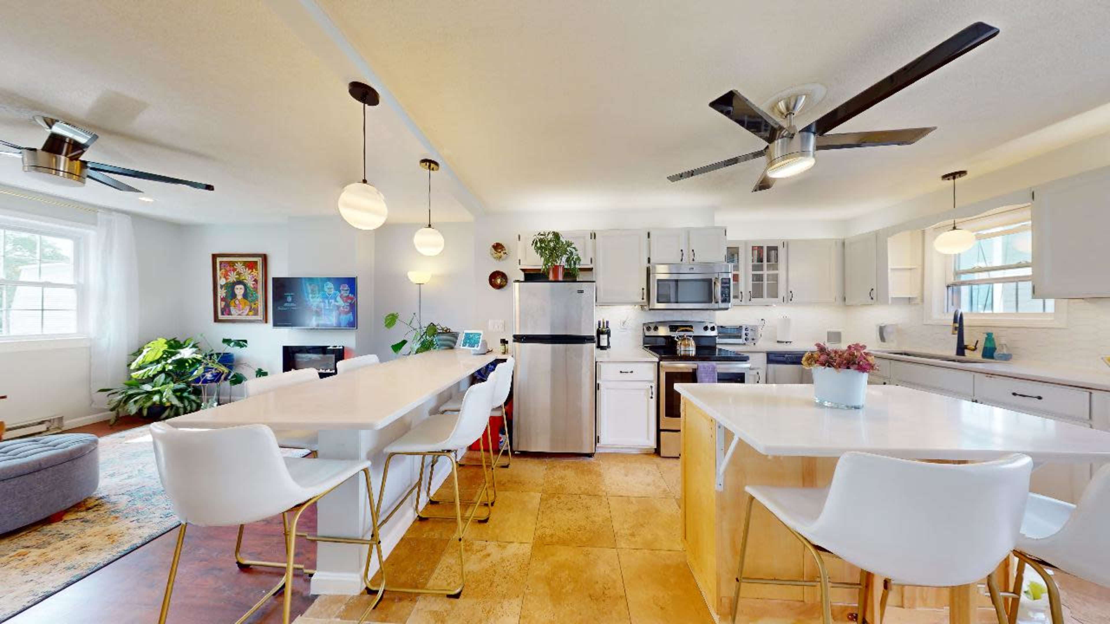 A modern kitchen and dining area featuring stainless steel appliances, white cabinetry, and a large island with seating.