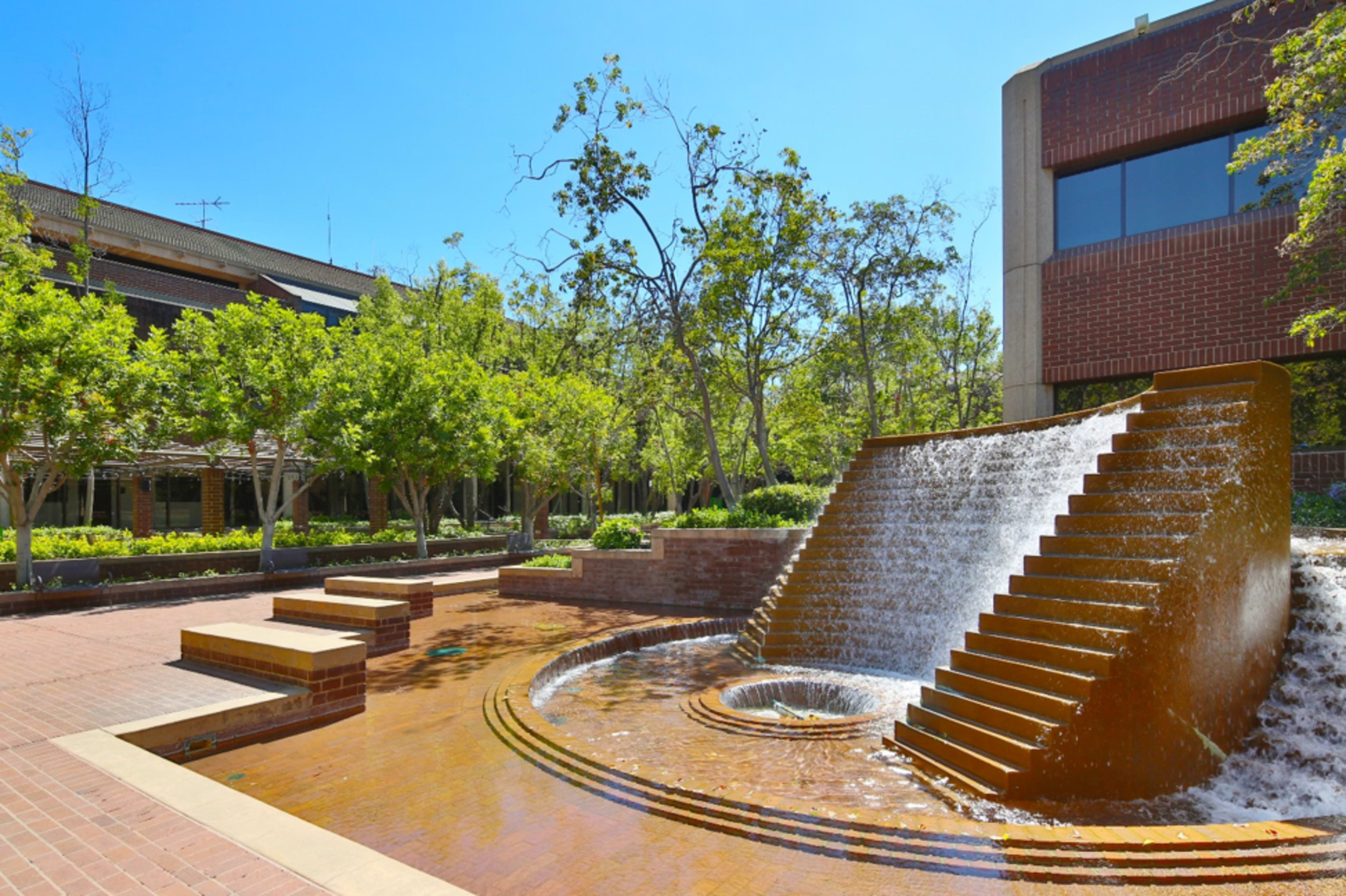 A landscaped courtyard featuring a fountain with cascading water and landscaped greenery.