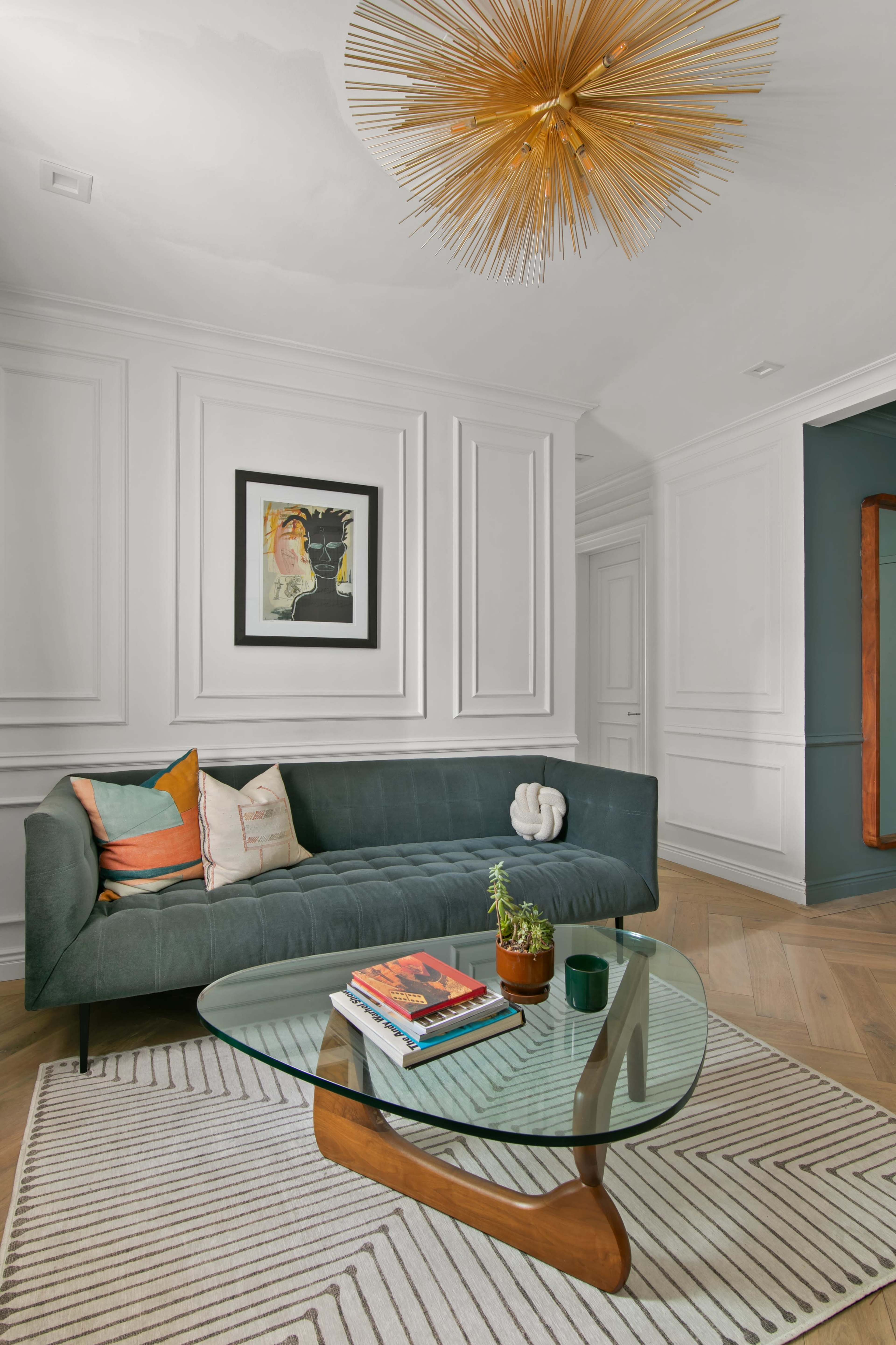 The image features a modern living room with a green sofa, a glass coffee table, and decorative items like books and a small plant.