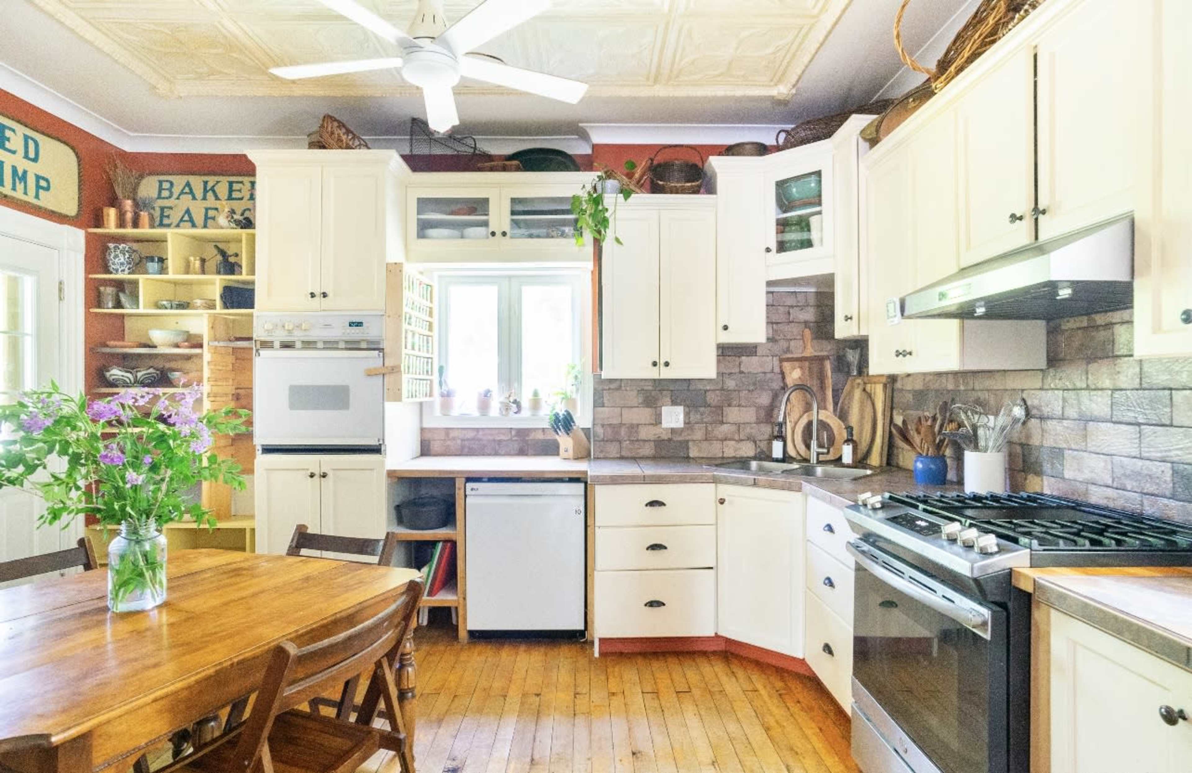 A well-organized kitchen featuring white cabinetry, a wooden table, and a variety of kitchen appliances.