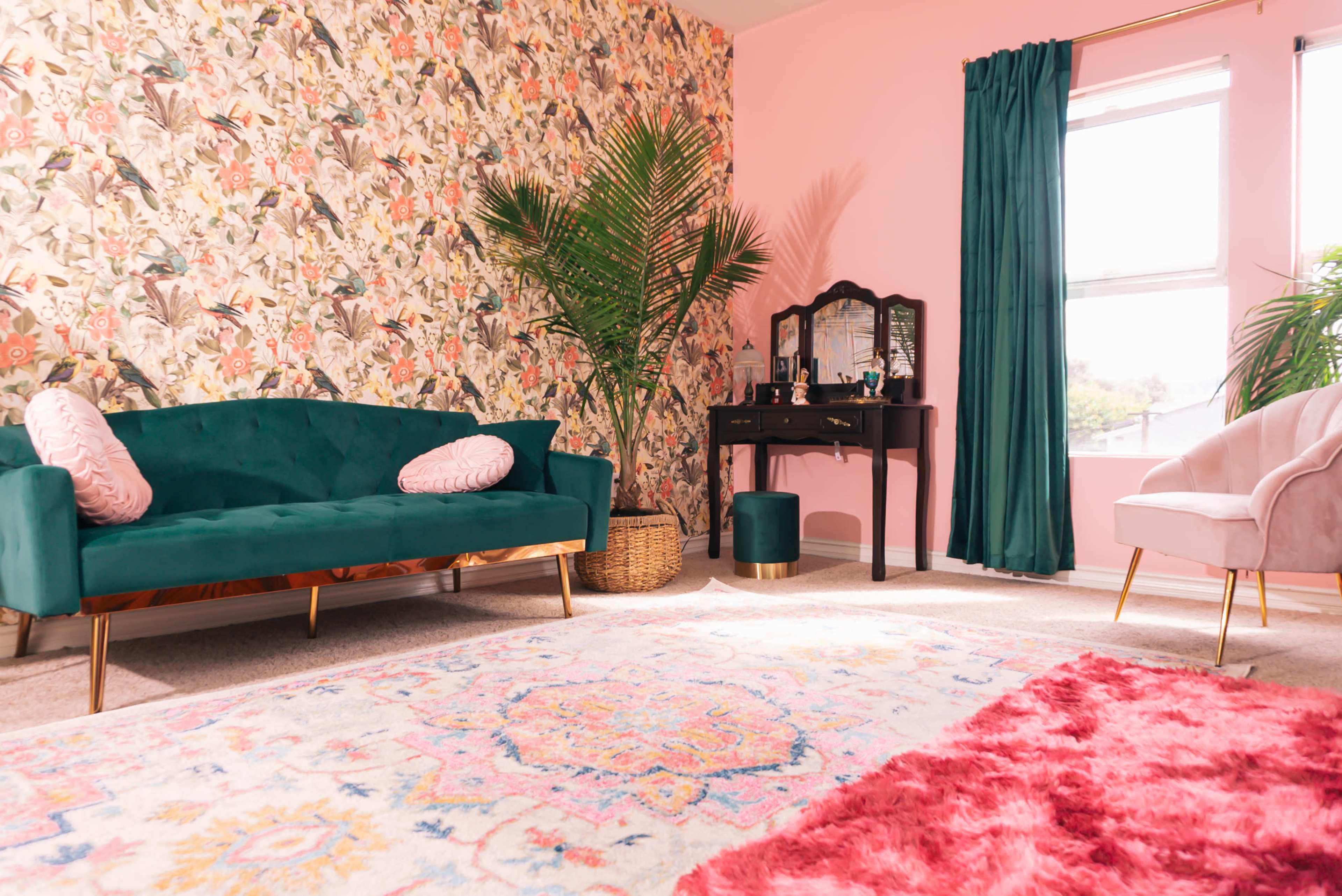 A visually vibrant living space featuring a teal sofa, a black vanity table, and a decorative floral wallpaper.