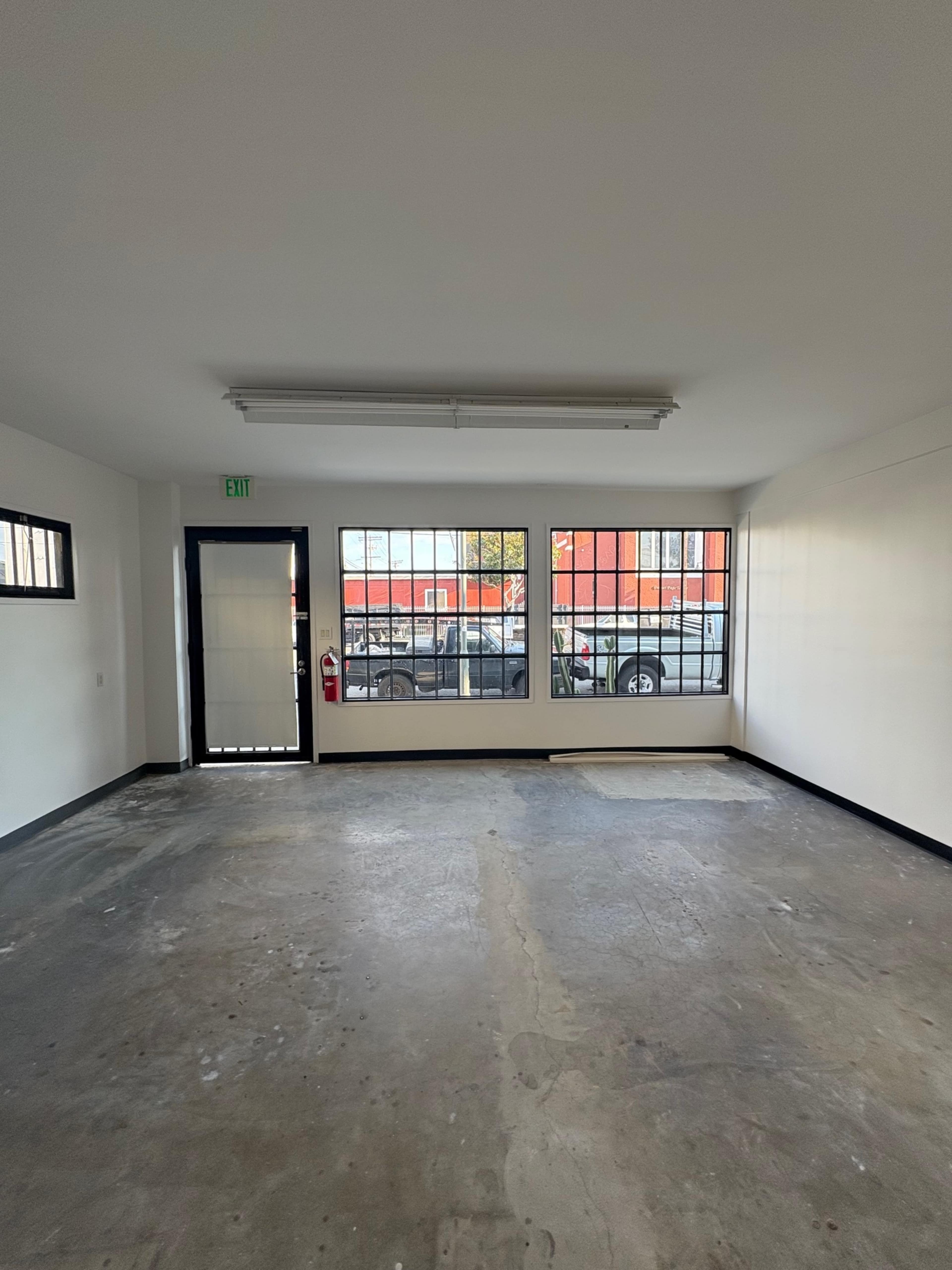 Empty modern storefront commercial space with concrete floors, large custom steel windows and oversized door. Image in South Los Angeles, Los Angeles, CA