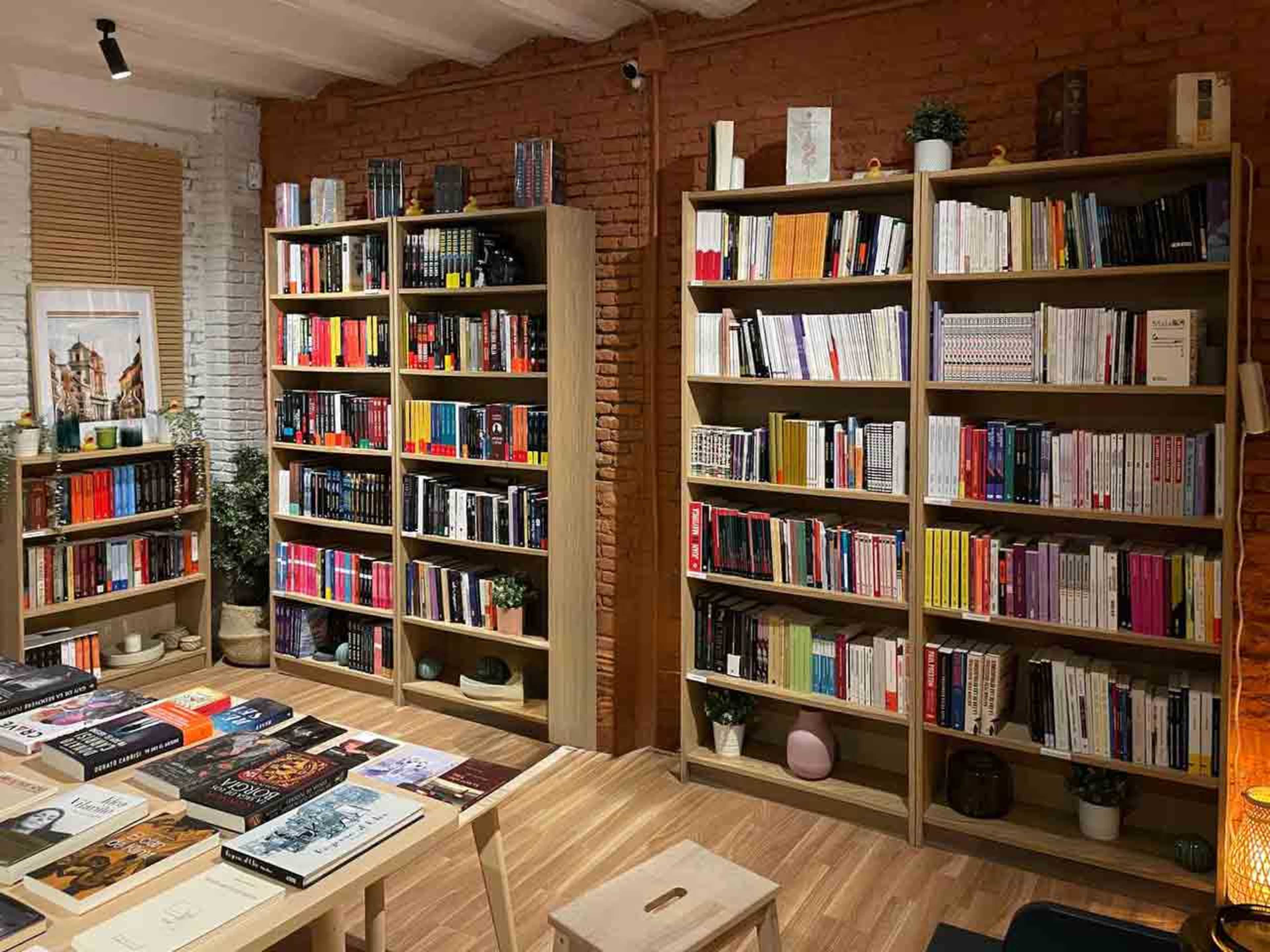 The image shows a cozy bookstore with tall wooden shelves filled with a variety of books, while a table displays additional books in front.