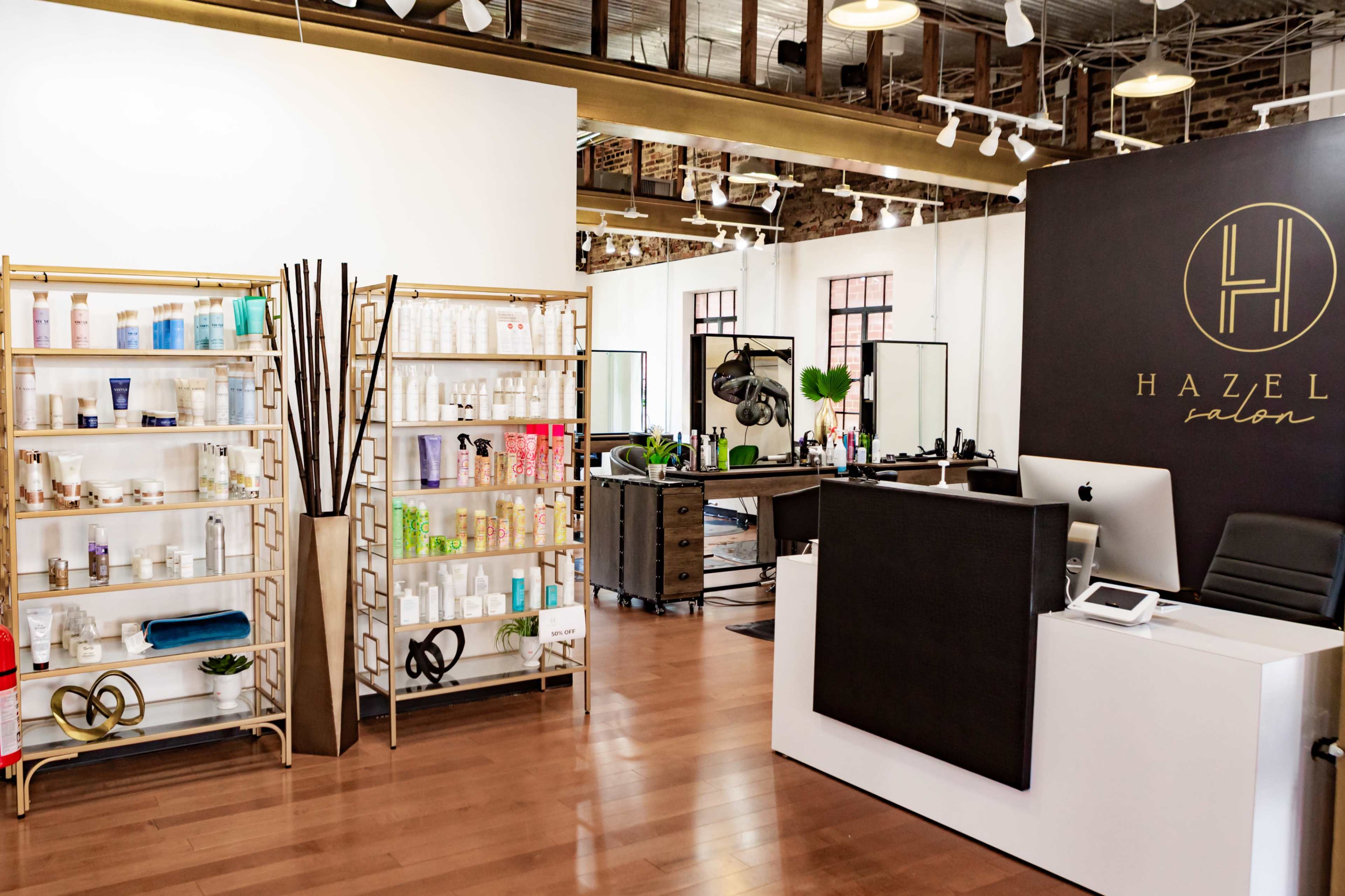 The image shows an interior view of a salon named Hazel, featuring organized shelves of hair and beauty products, a reception desk, and several styling stations.