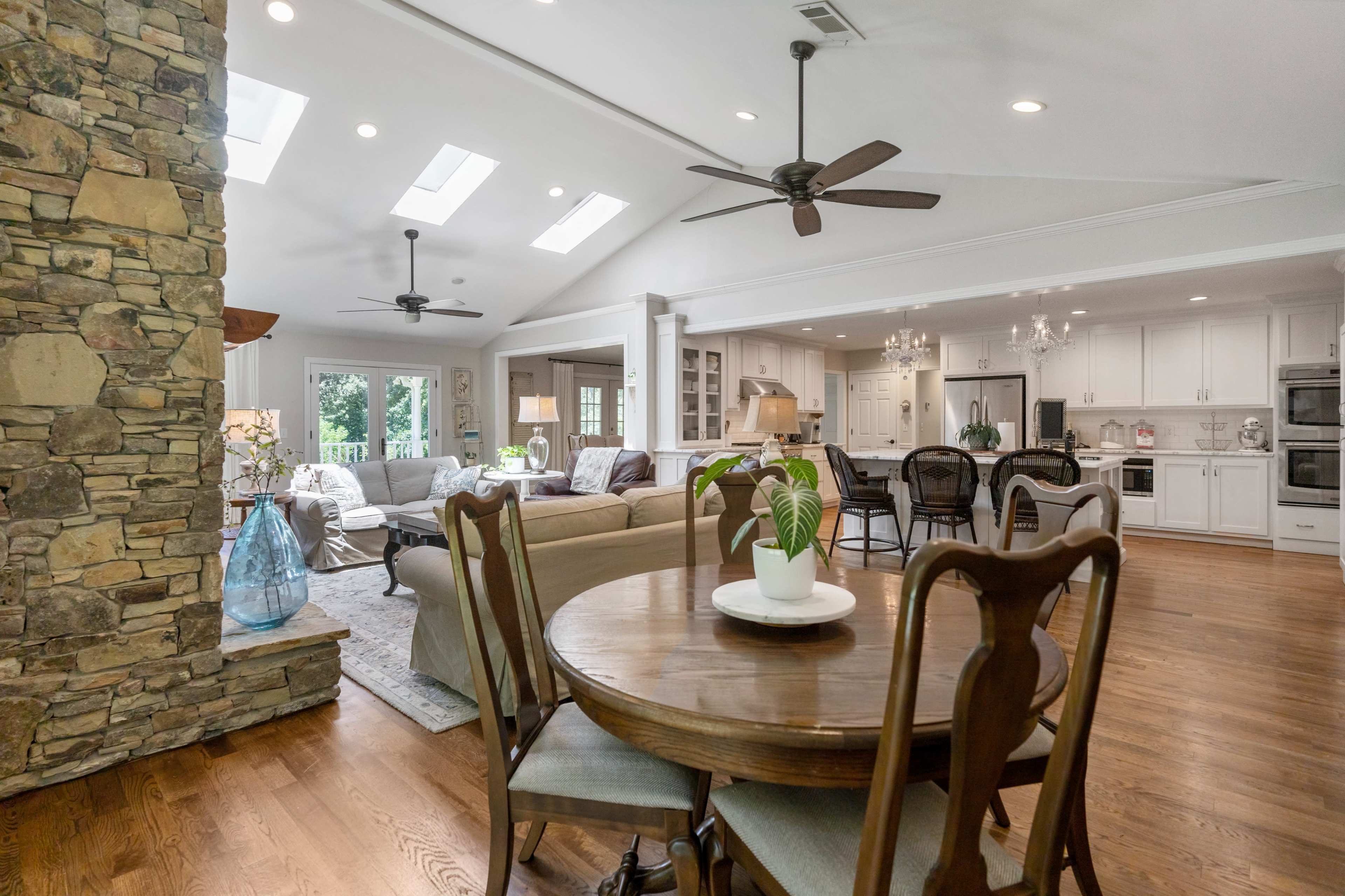 An open-concept living space with a stone wall, skylights, a dining area, and a modern kitchen.