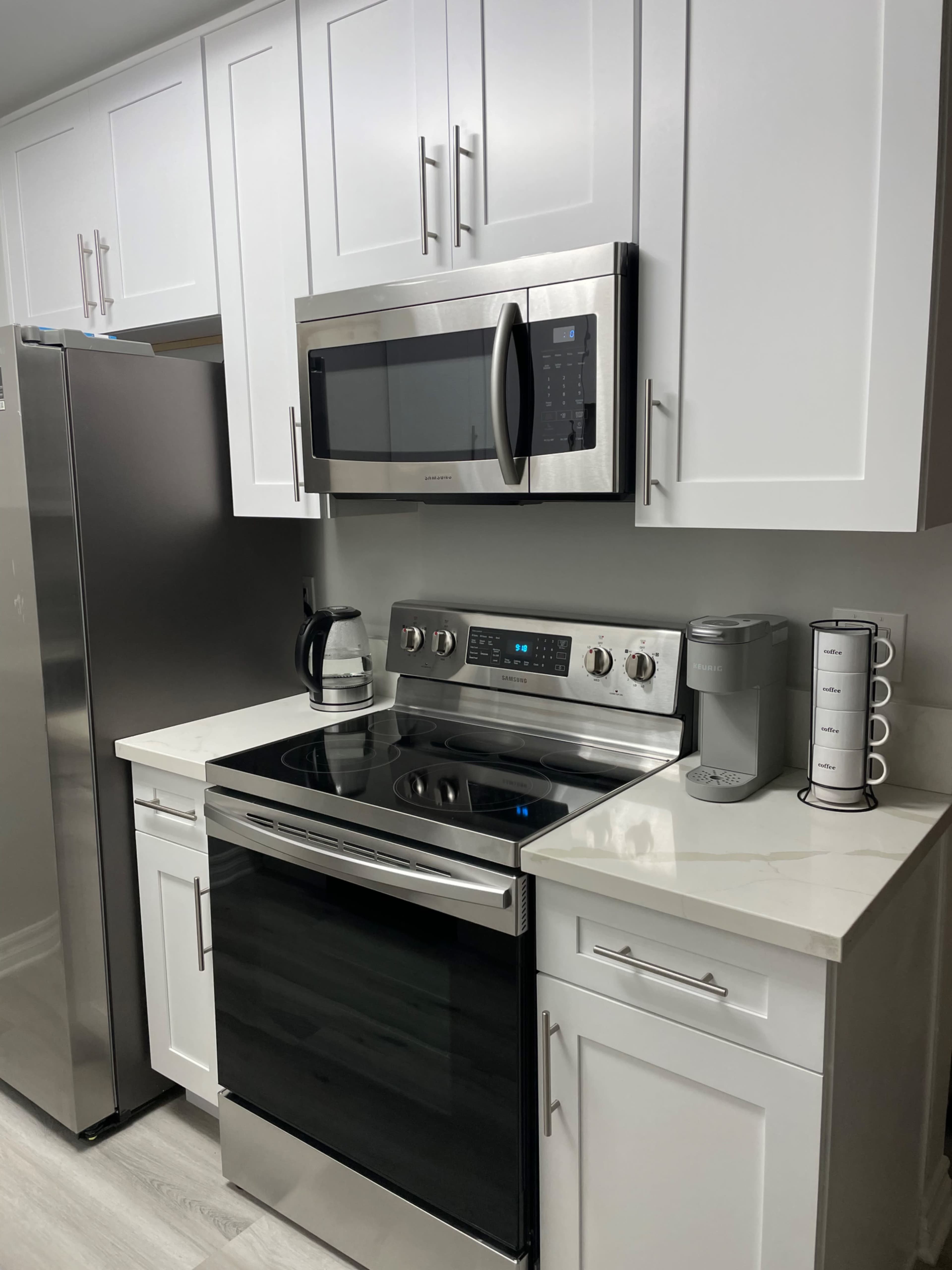 A modern kitchen with stainless steel appliances, white cabinetry, and a smooth countertop.