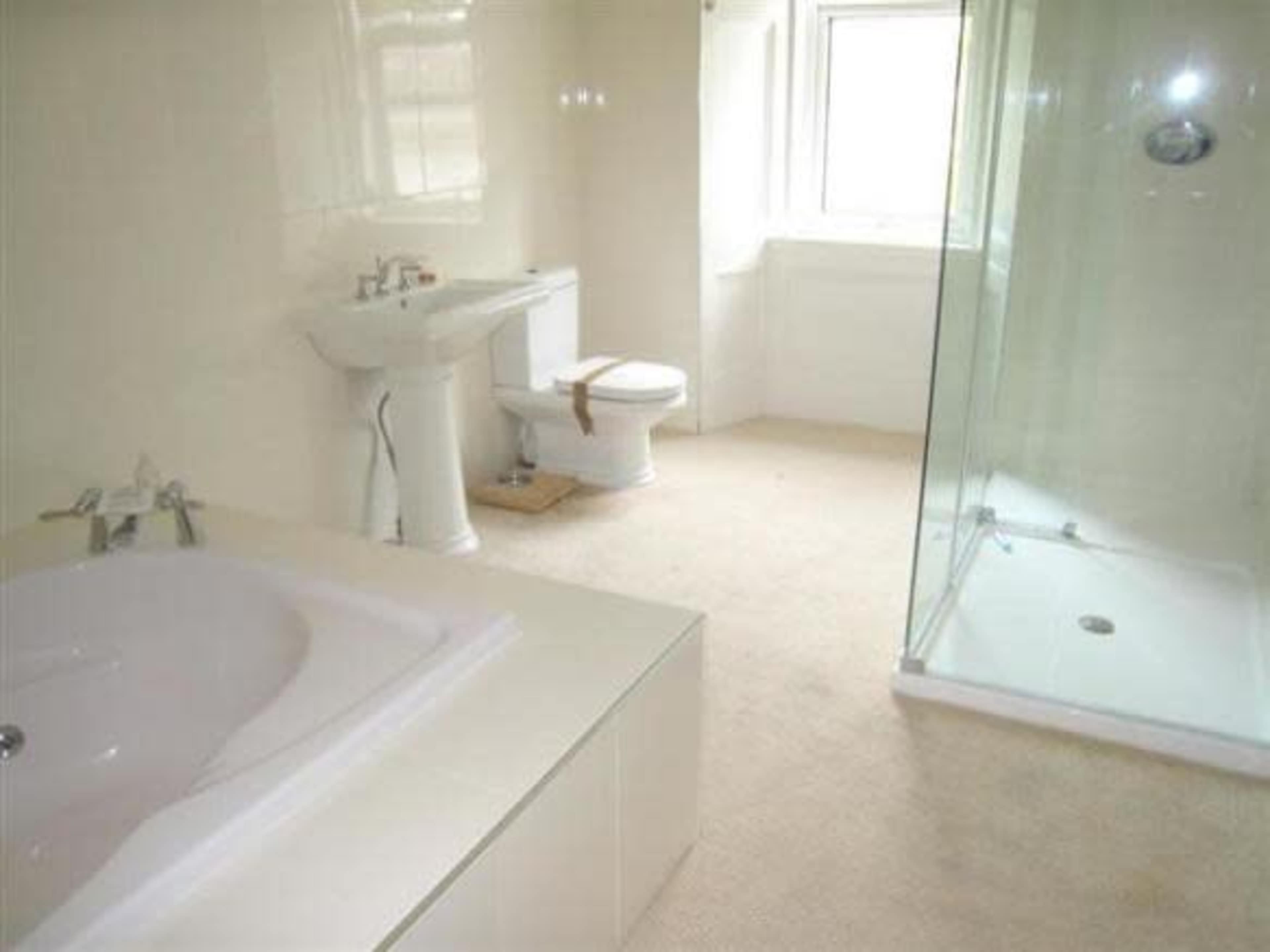 A bathroom with a bathtub, a shower with a glass enclosure, a sink, and a toilet.