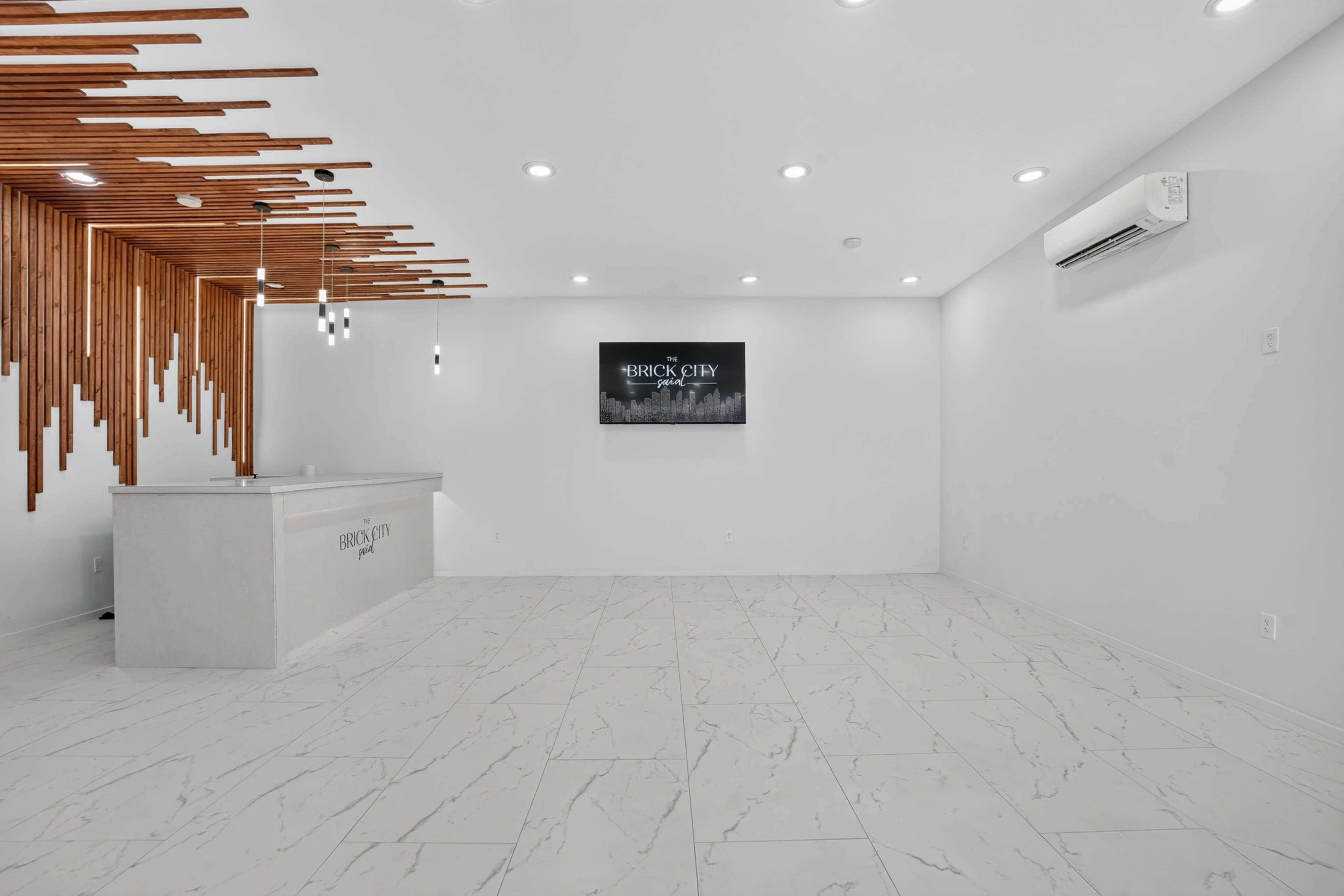 The image shows a modern reception area with a sleek front desk, wooden wall accents, and minimalistic decor under bright lighting.