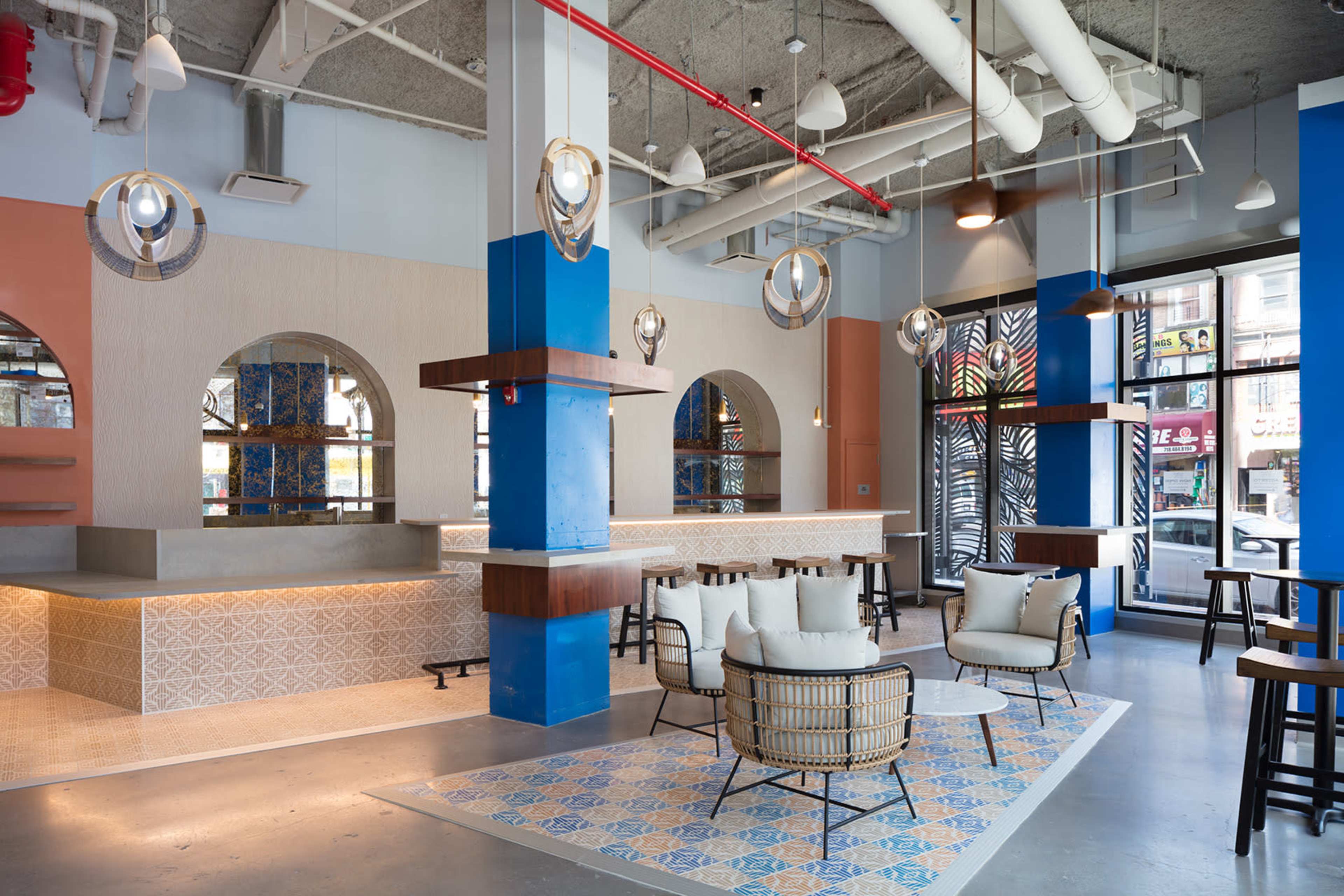 A modern, brightly lit café with a spacious layout featuring stylish seating areas, decorative arches, and hanging light fixtures.