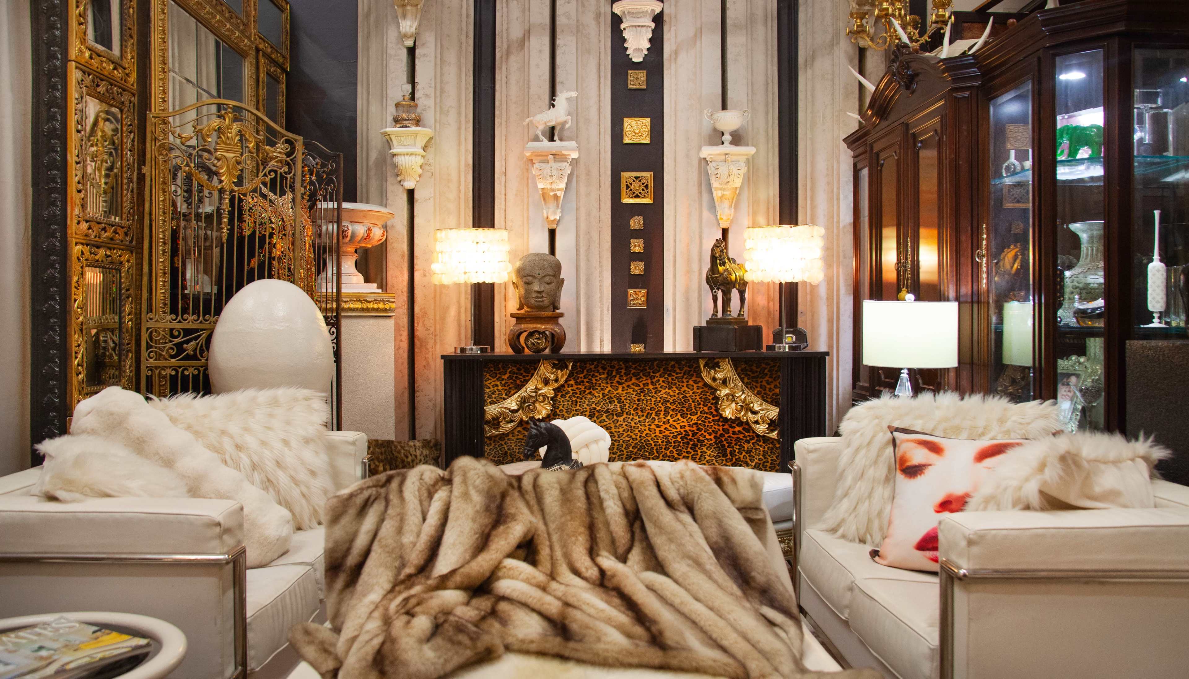 The image depicts a stylish living room adorned with ornate decorations, including a variety of sculptures, lighting fixtures, and plush furnishings.