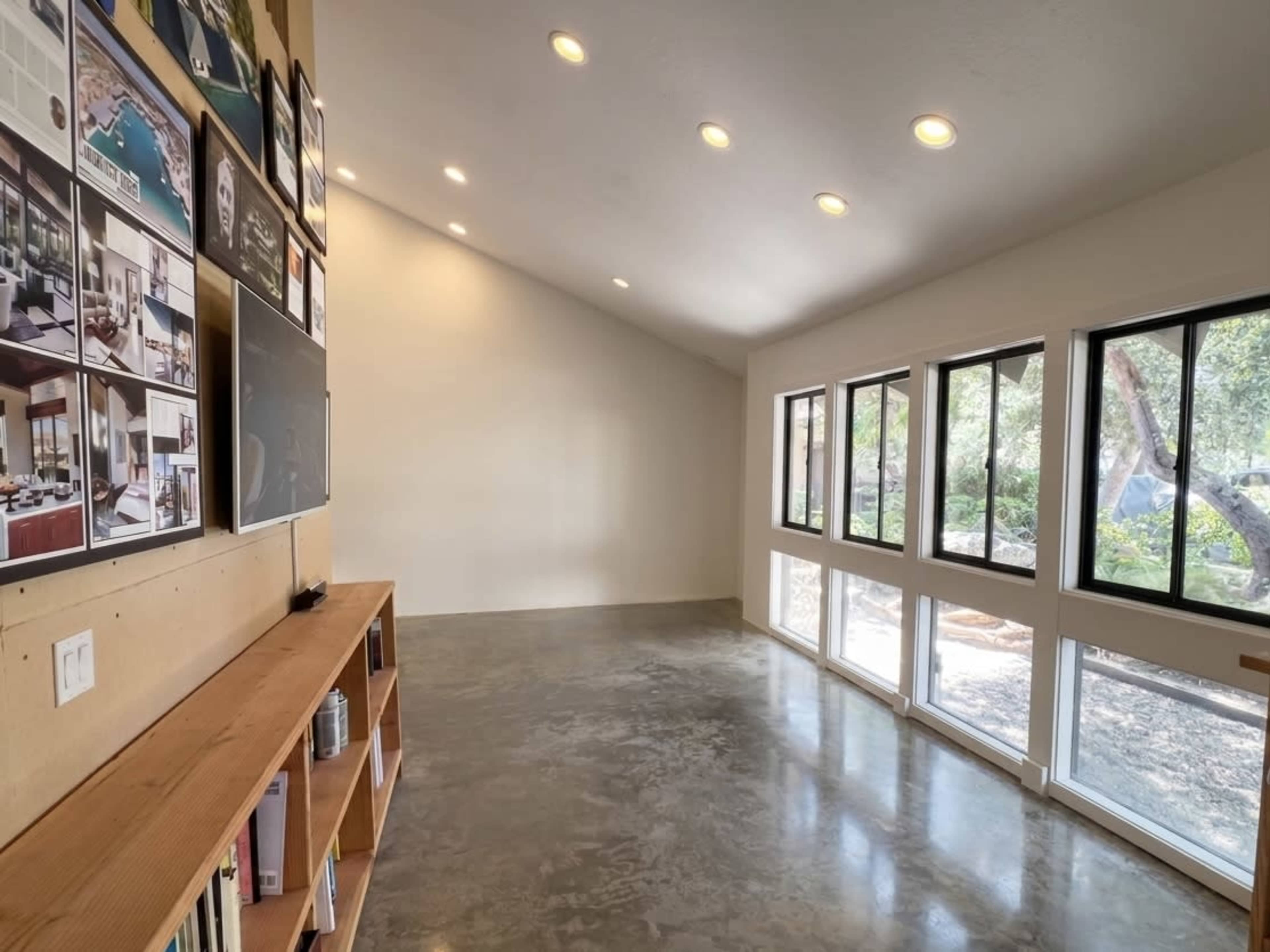 The image shows a bright, open interior space with large windows, a high ceiling, and polished concrete flooring.