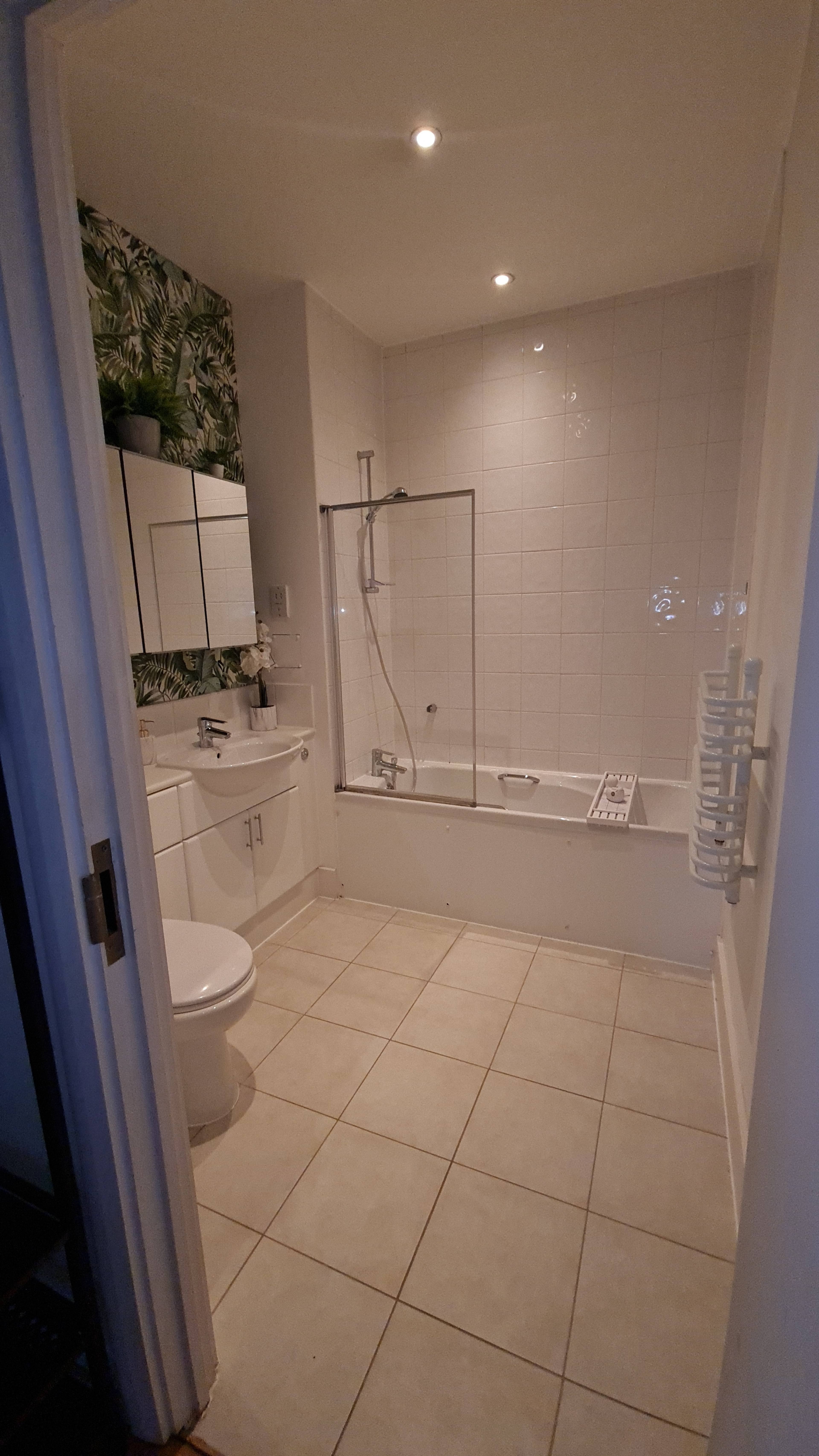 A modern bathroom with a shower and bathtub combo, large mirrors, and tiled flooring.
