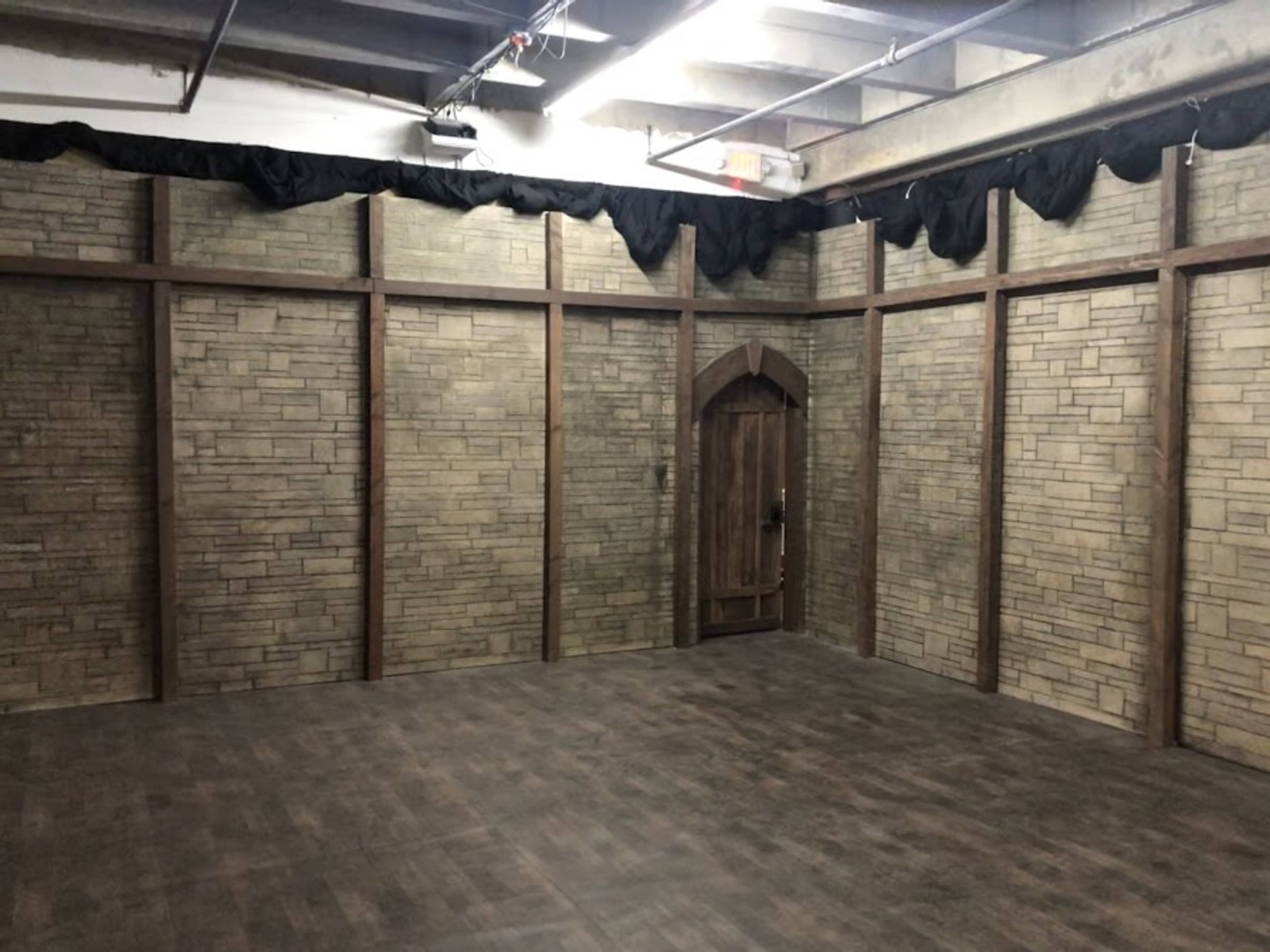 A room with stone-patterned walls, wooden accents, and a single door on one side.
