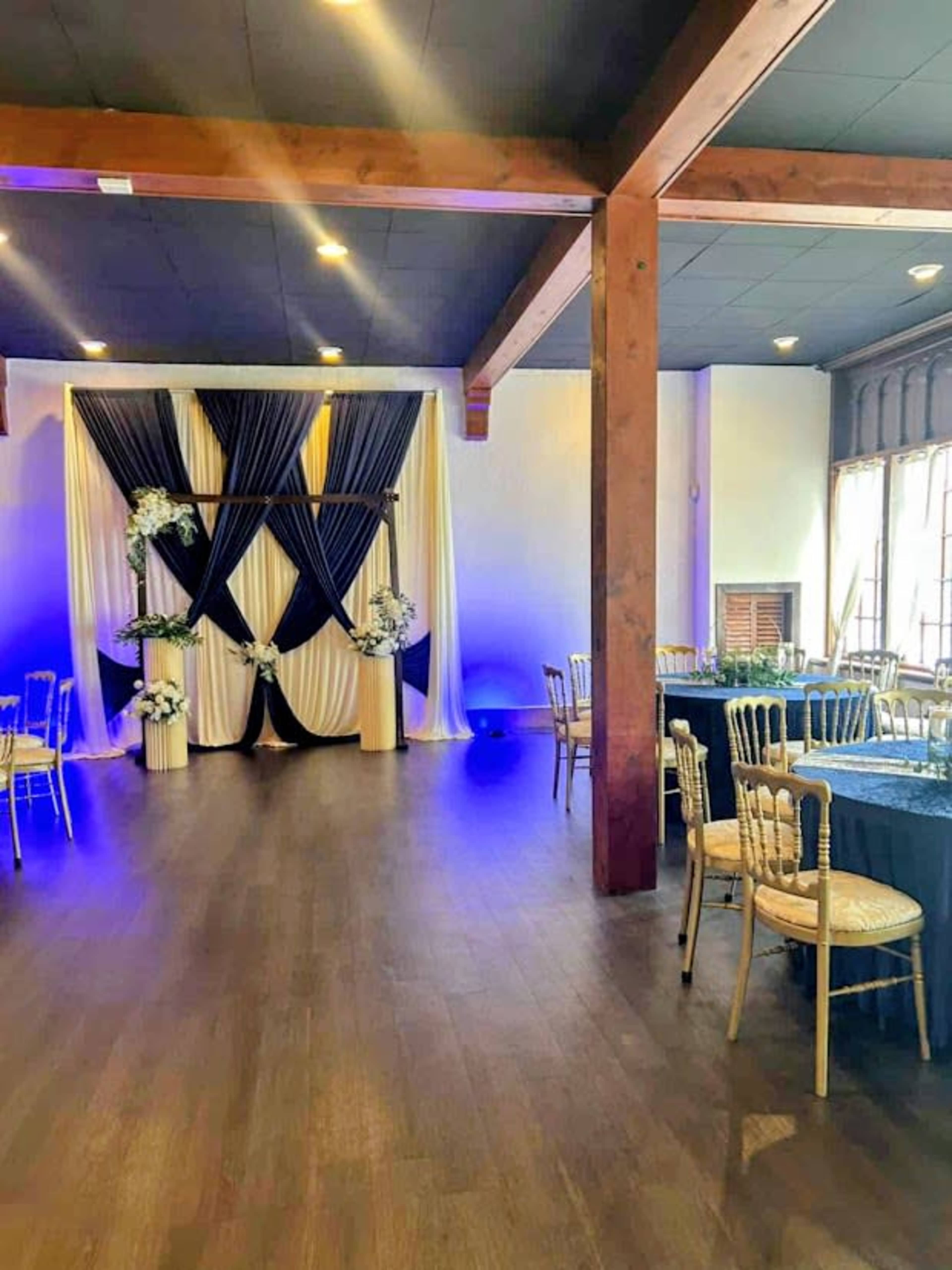 The image depicts a banquet hall featuring elegant drapery and tables arranged for an event, illuminated by soft lighting.