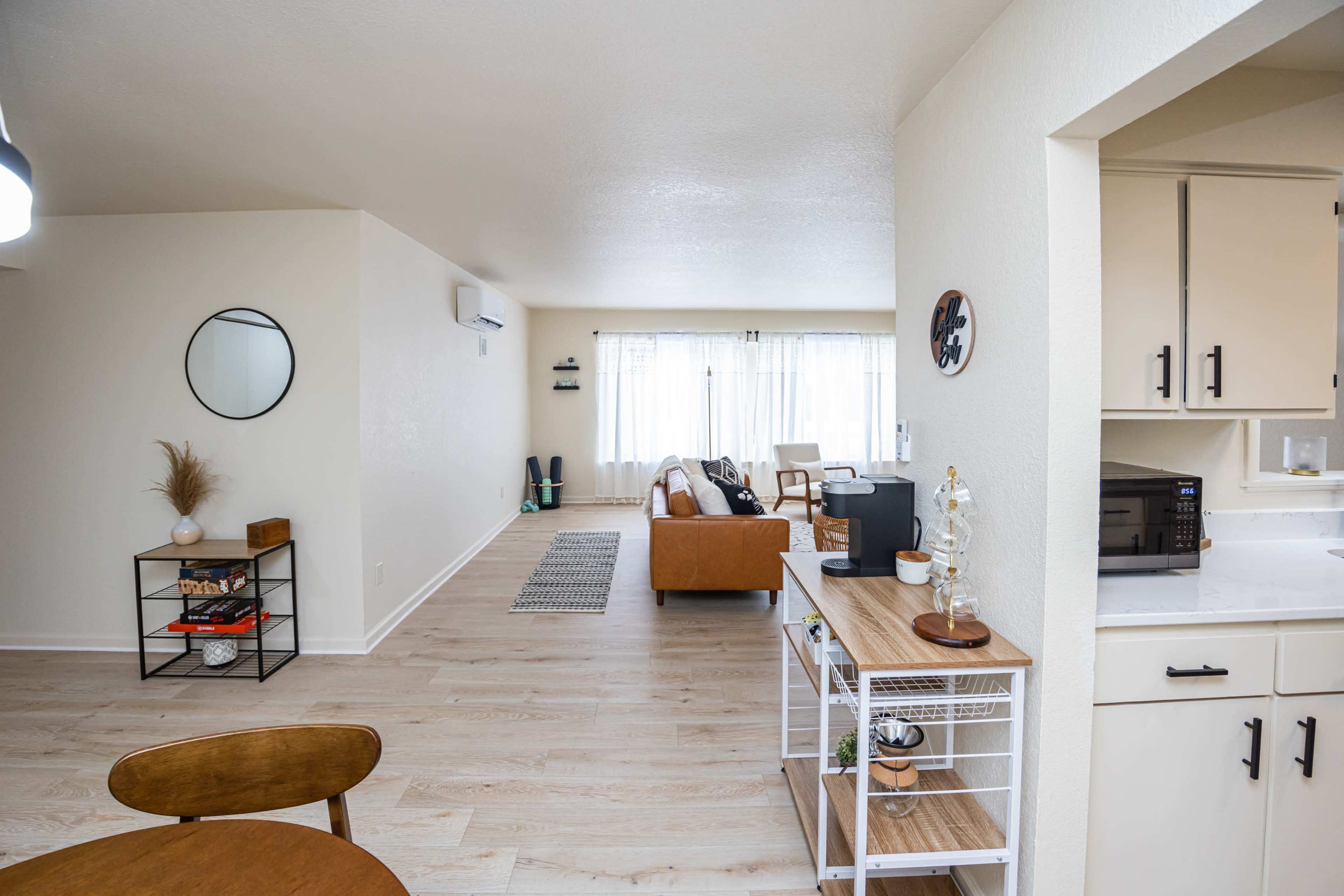 A modern living space features a cozy seating area, a dining table, and a kitchen area with minimal decor and light wooden floors.
