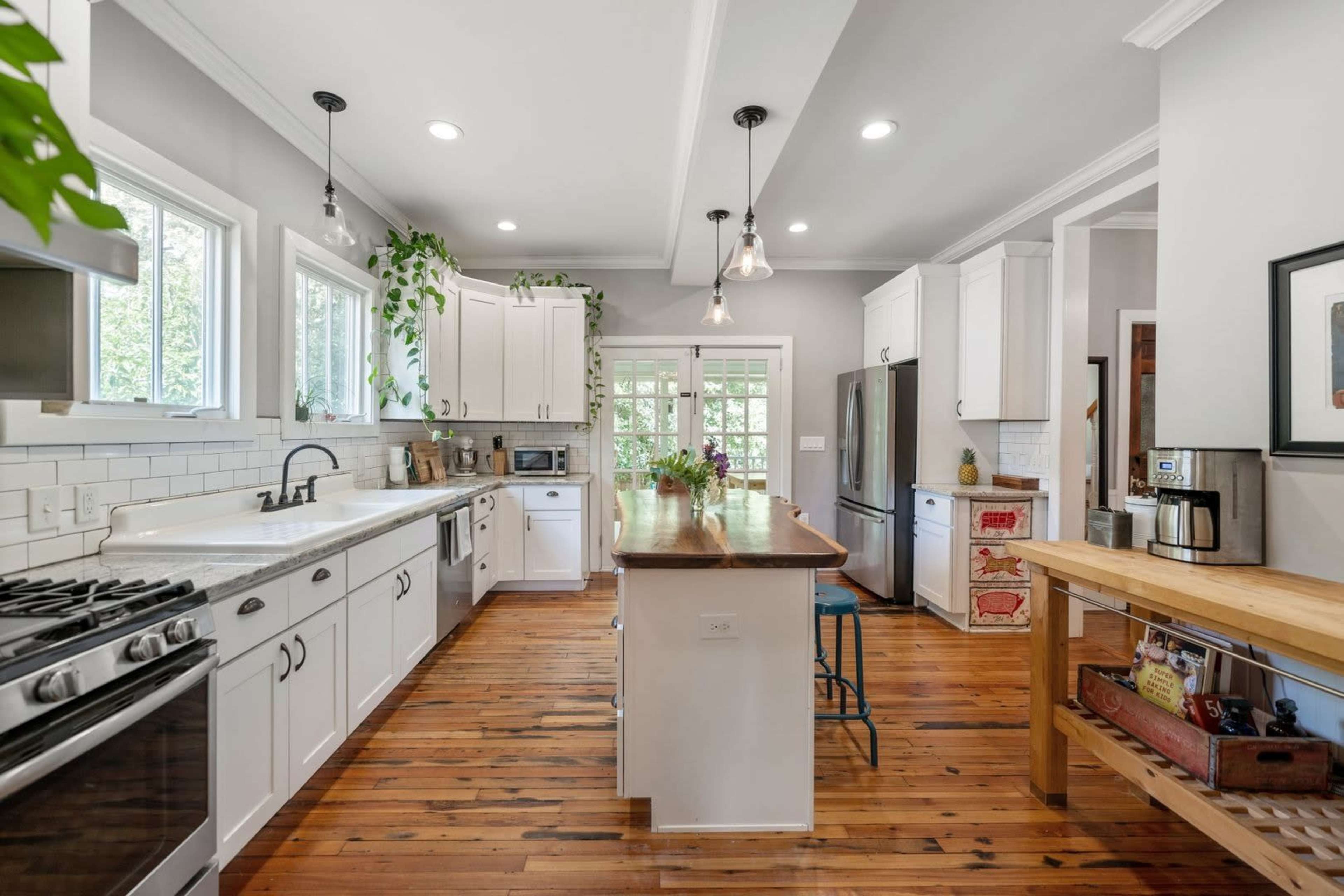 A spacious, well-lit kitchen features white cabinetry, a center island with seating, and hardwood floors, enhanced by natural light from multiple windows.
