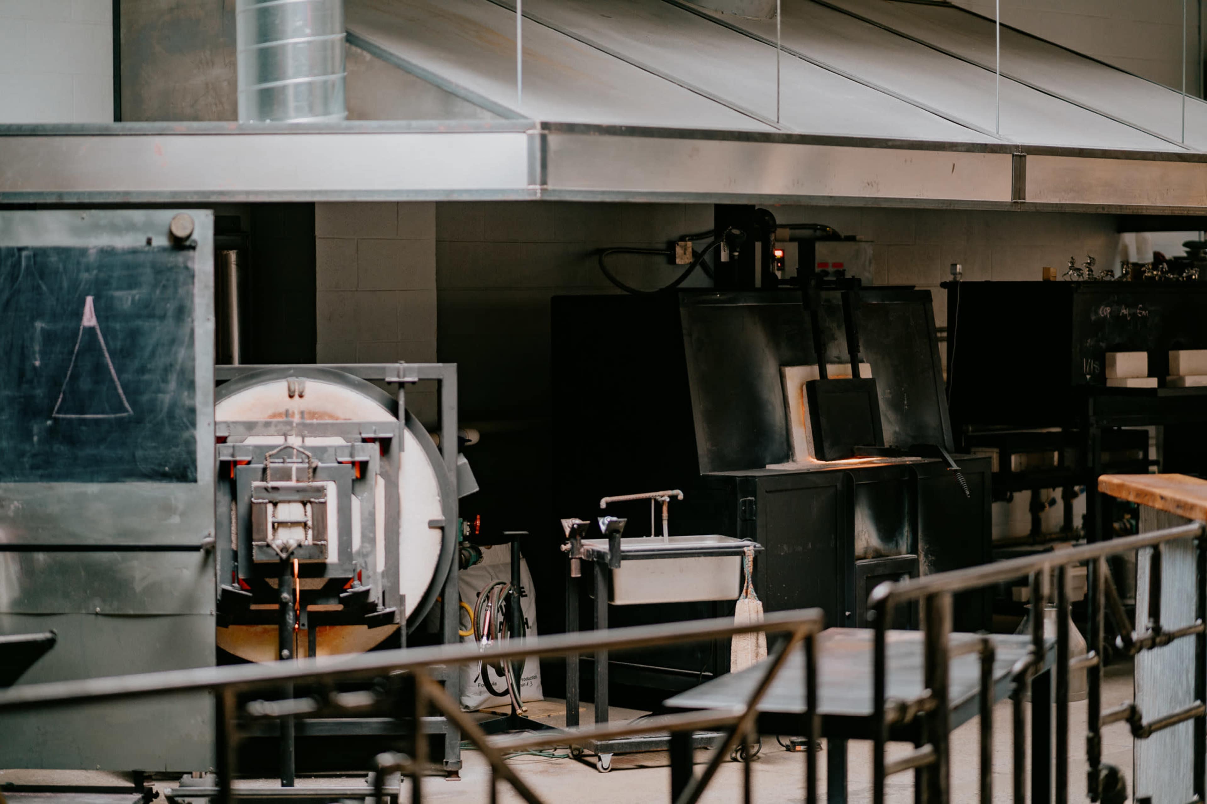 A glassblowing workshop equipped with furnaces and various glassworking tools.