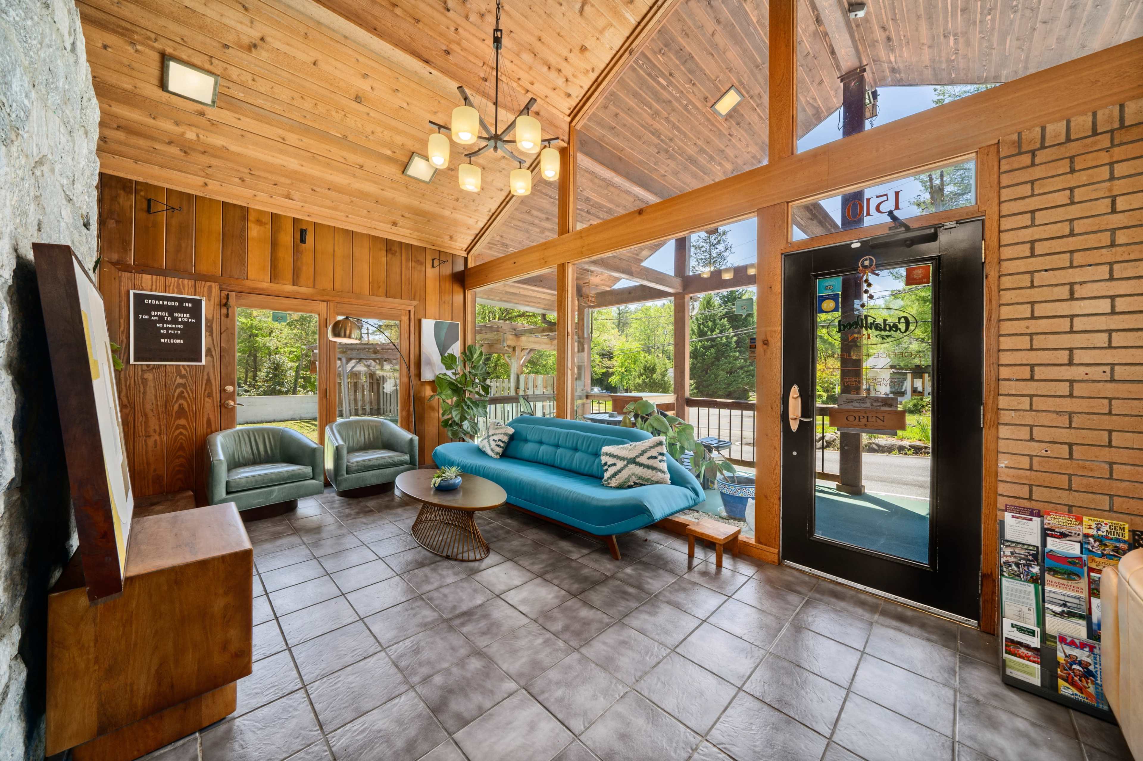 A spacious waiting area with a modern blue sofa, two green chairs, and large windows that provide natural light.