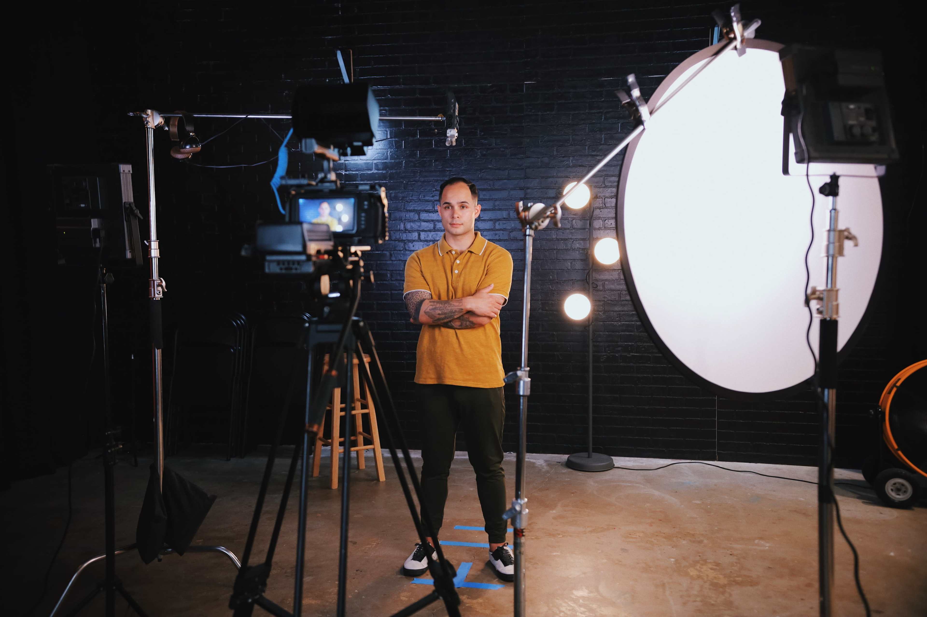 A man stands in a photo studio surrounded by cameras and lighting equipment.