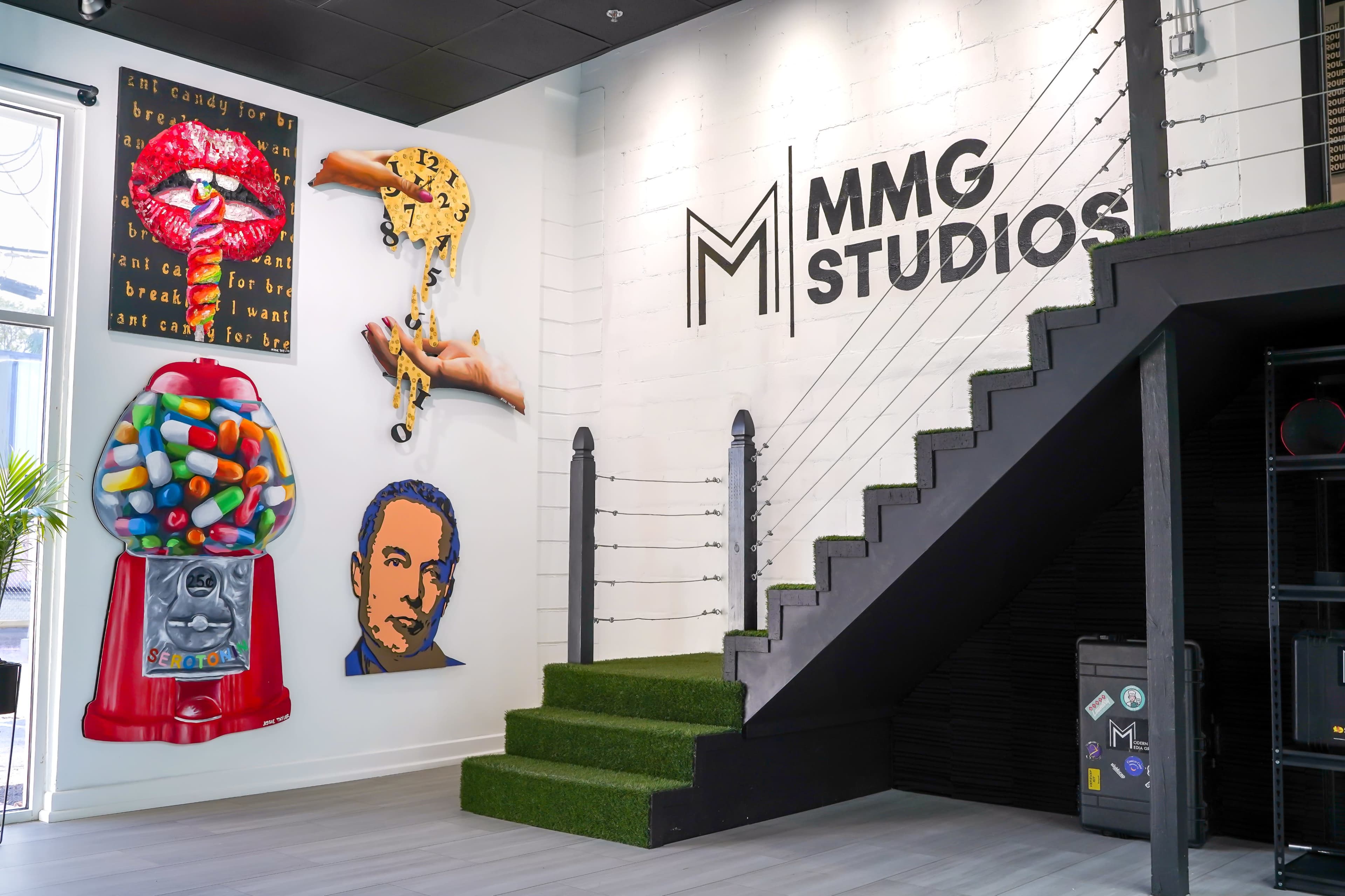 A creatively designed studio entrance featuring a staircase, colorful wall art, and a gumball machine.