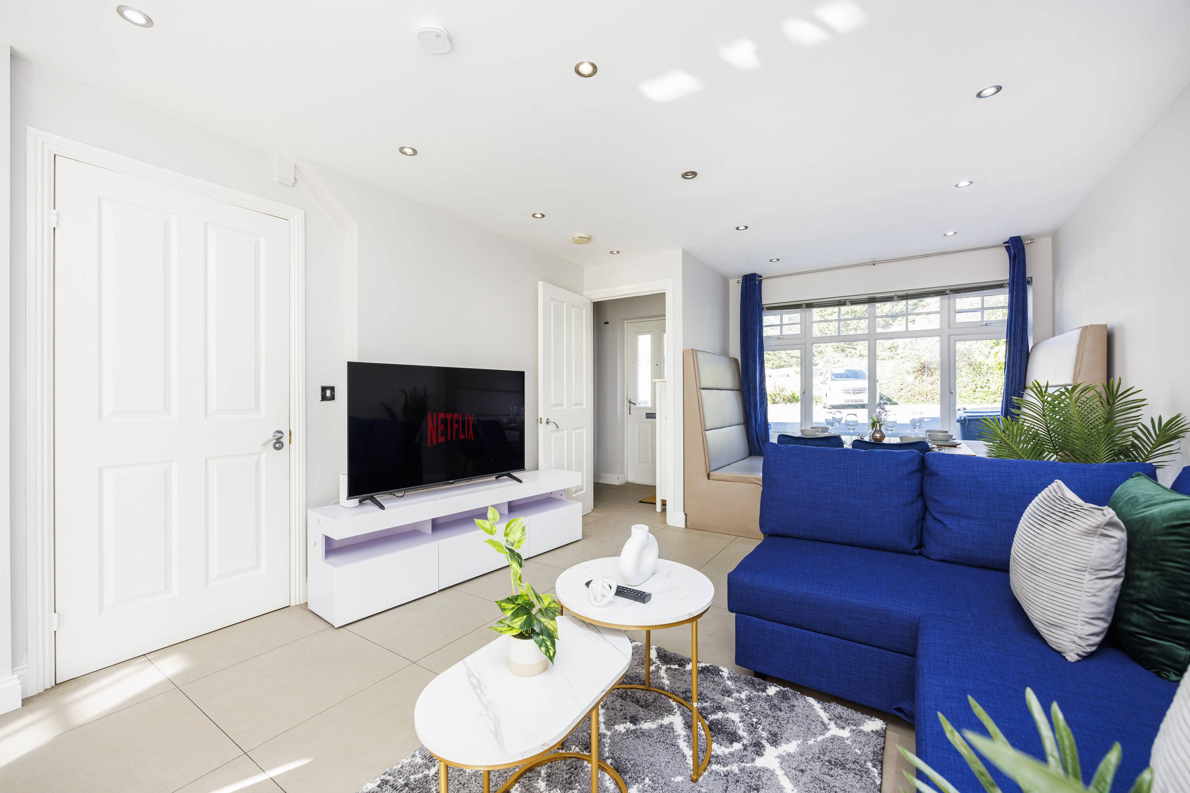 A modern living room with a blue sofa, a coffee table, and a television displaying the Netflix logo.