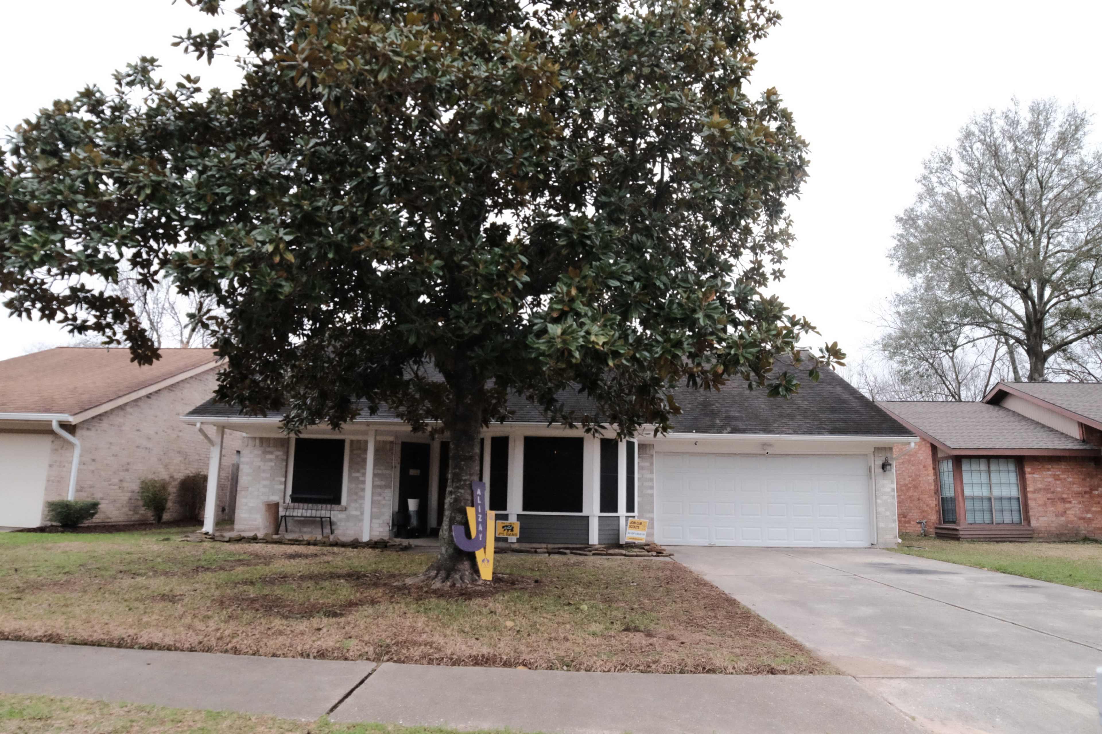 A single-story house with a large magnolia tree in the front yard and a garage on the right side.