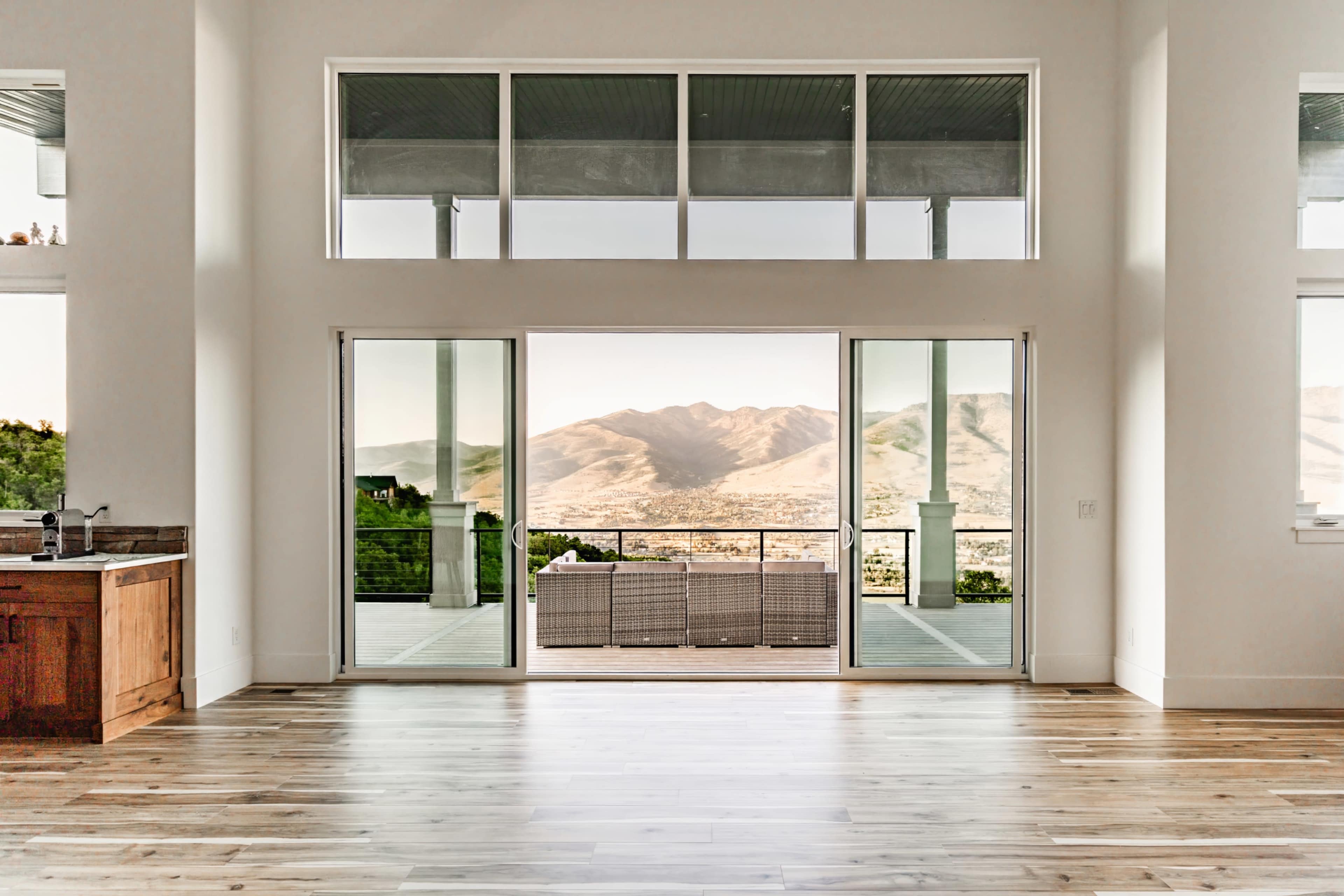 A spacious interior with large glass doors opens to a balcony that overlooks a mountain view.