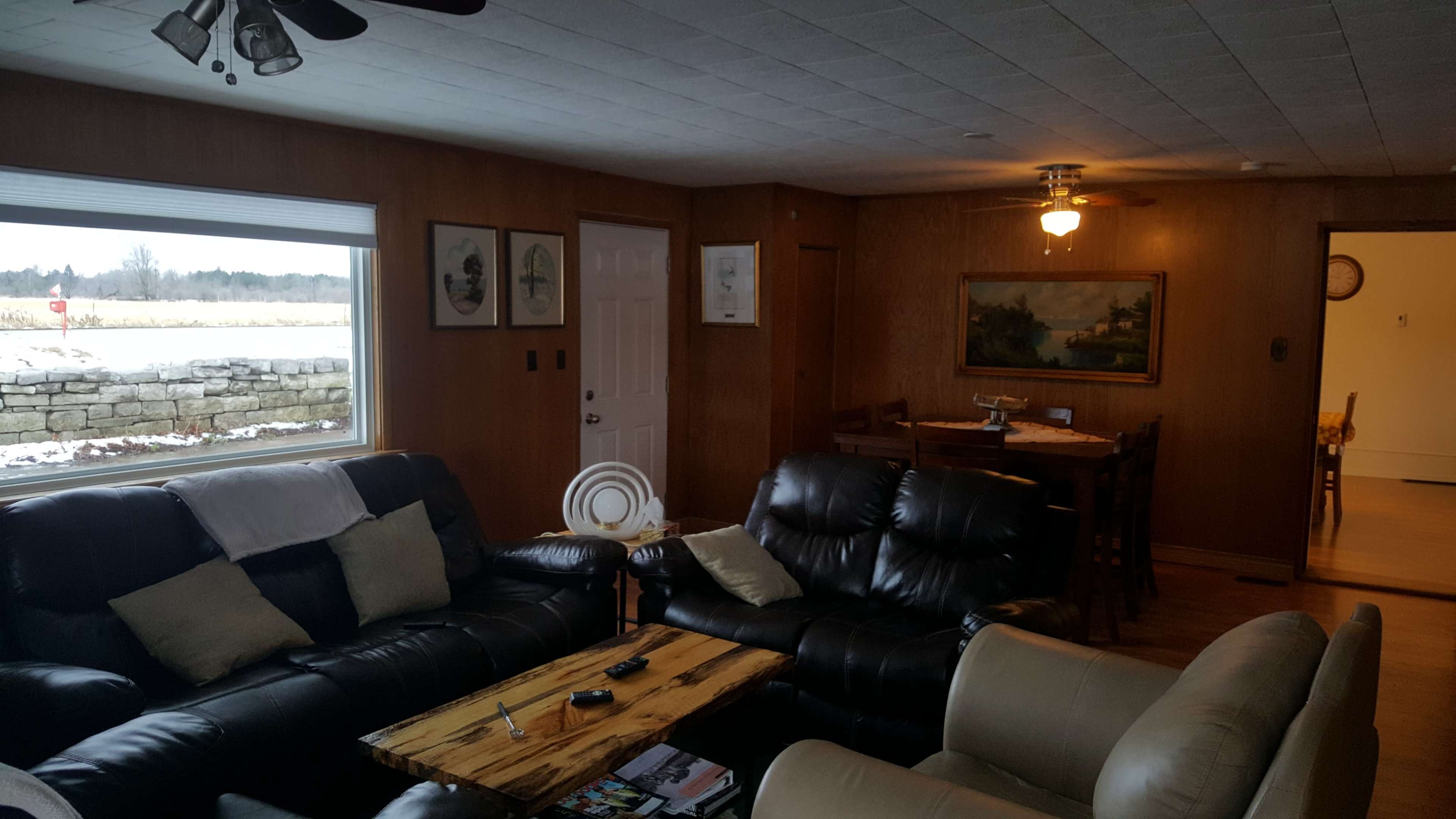 A cozy living room with two leather sofas, a wooden coffee table, and a dining area visible in the background.