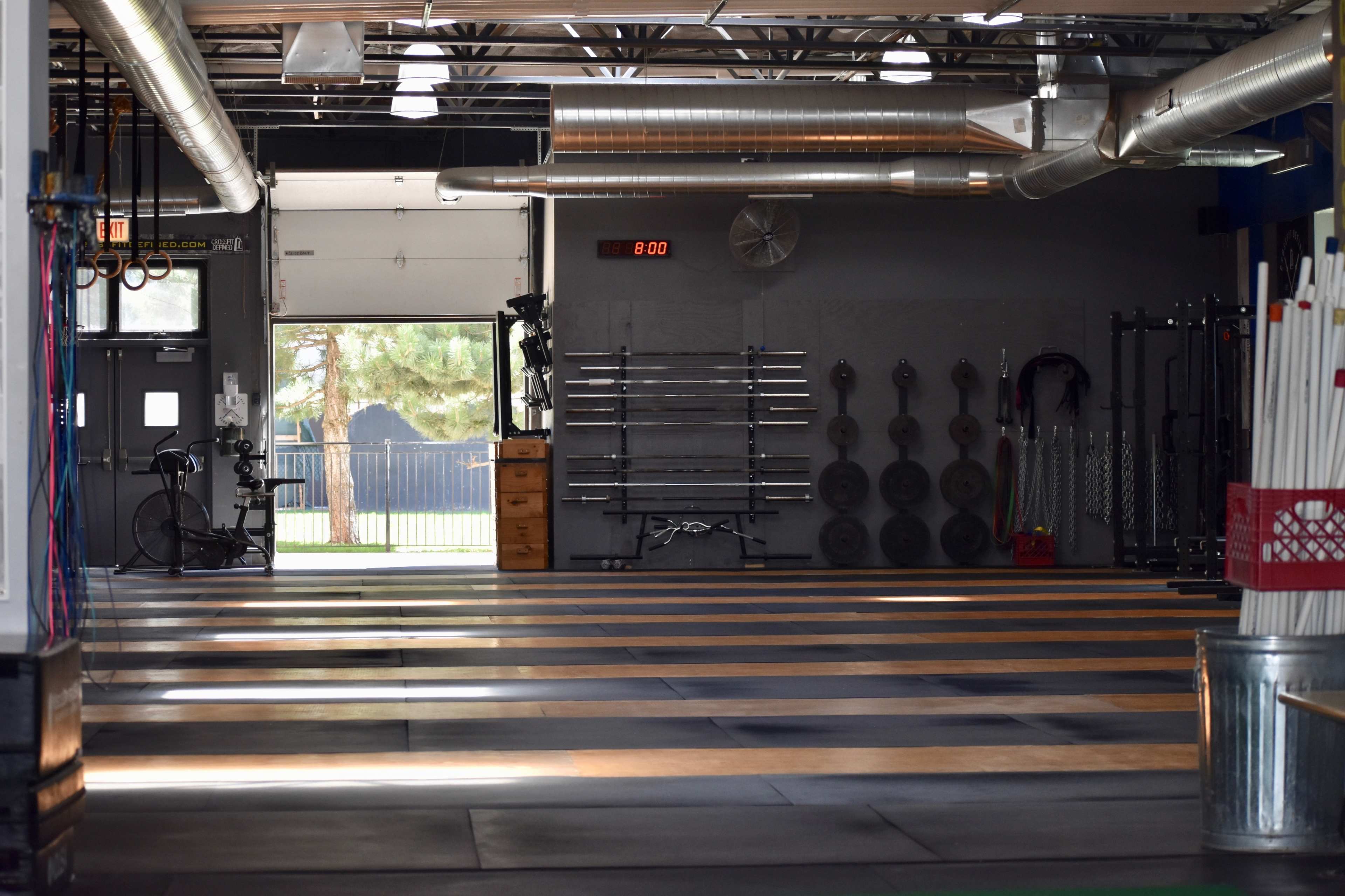 An empty gym interior with equipment storage and a large open workout area under industrial lighting.
