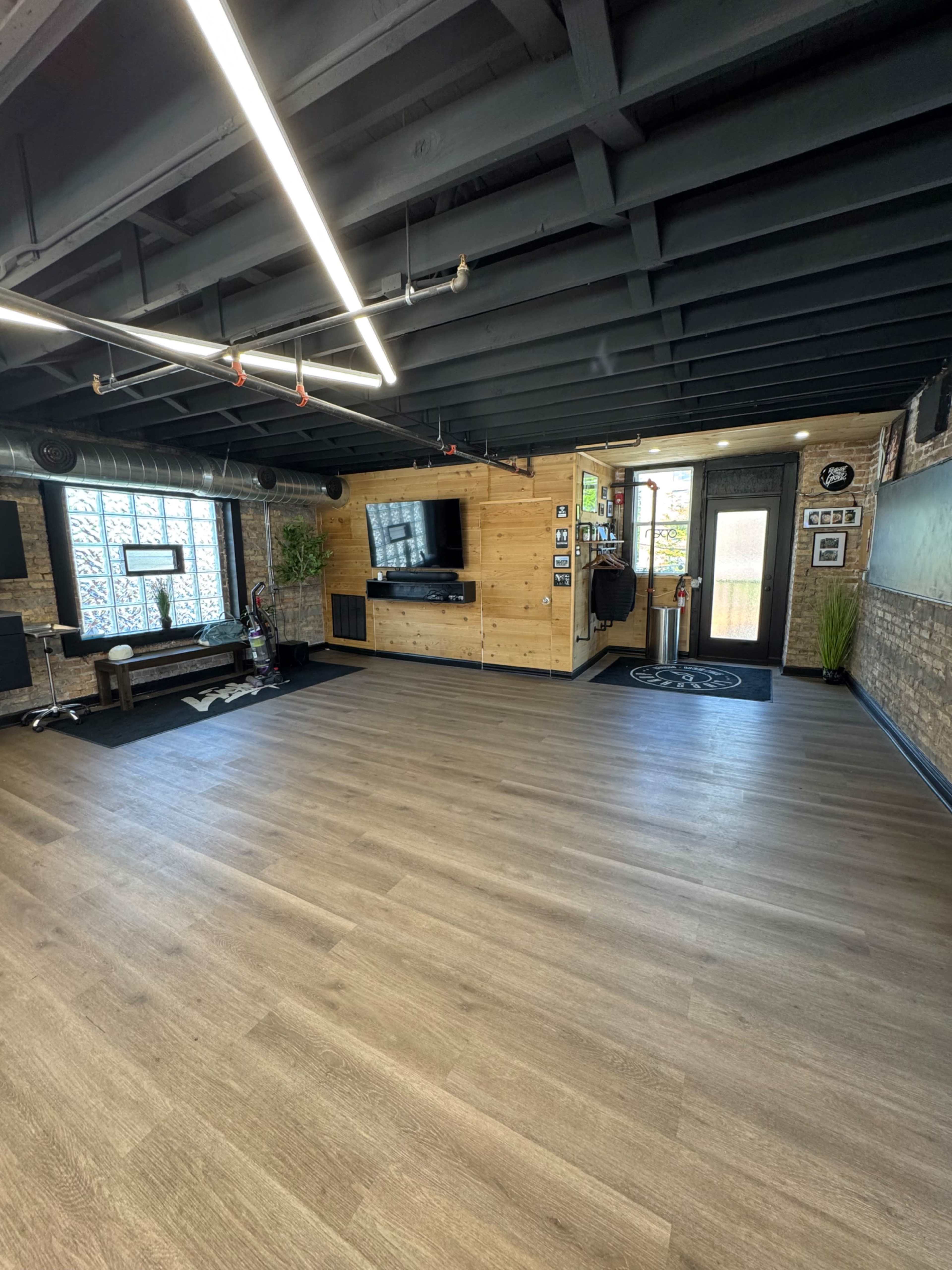 The image shows a spacious, modern interior with wooden paneling, a large TV on the wall, and a clean, minimalistic design.