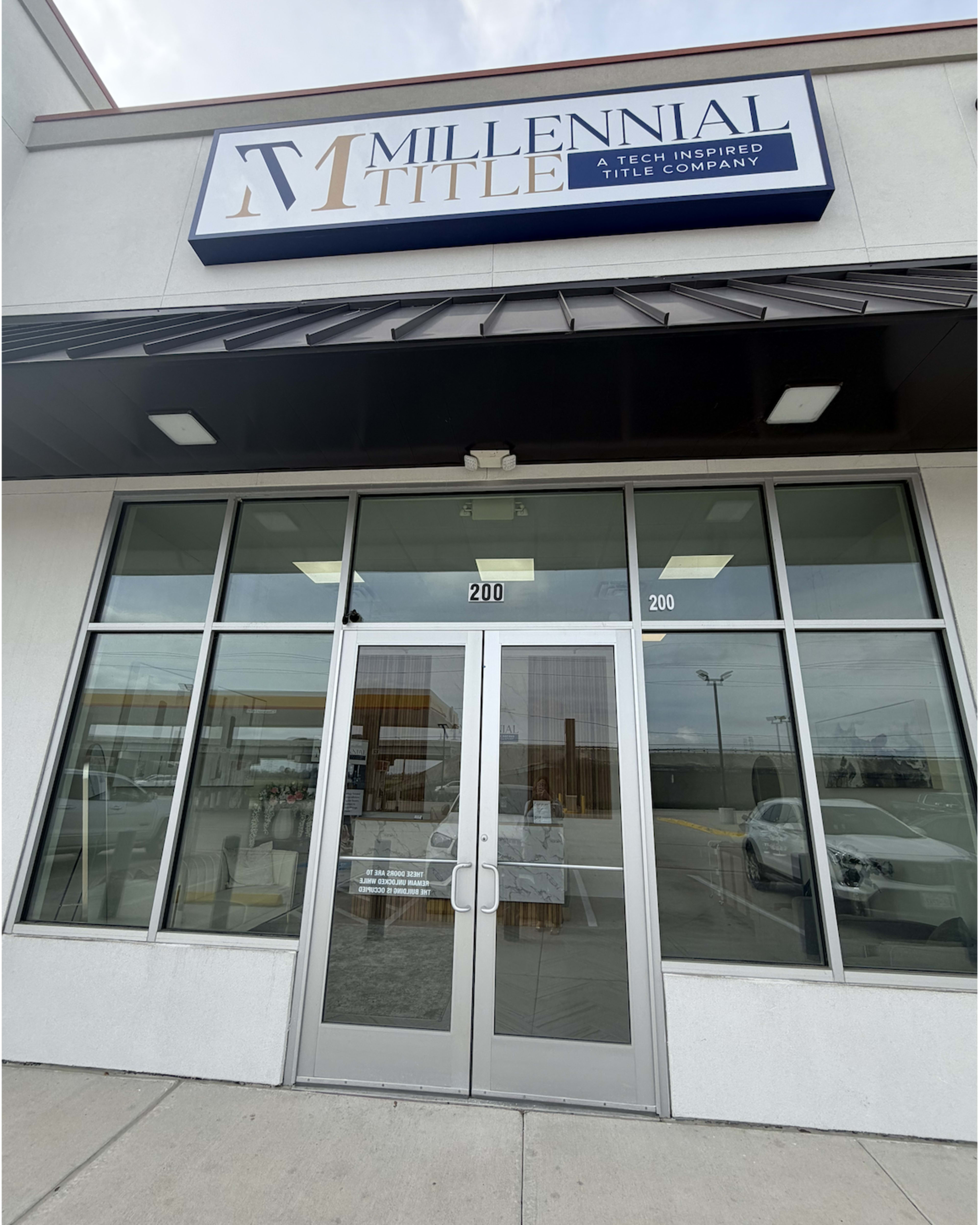 The image shows the entrance of a commercial building featuring a glass door with the sign for "Millennial Title Company" above it.