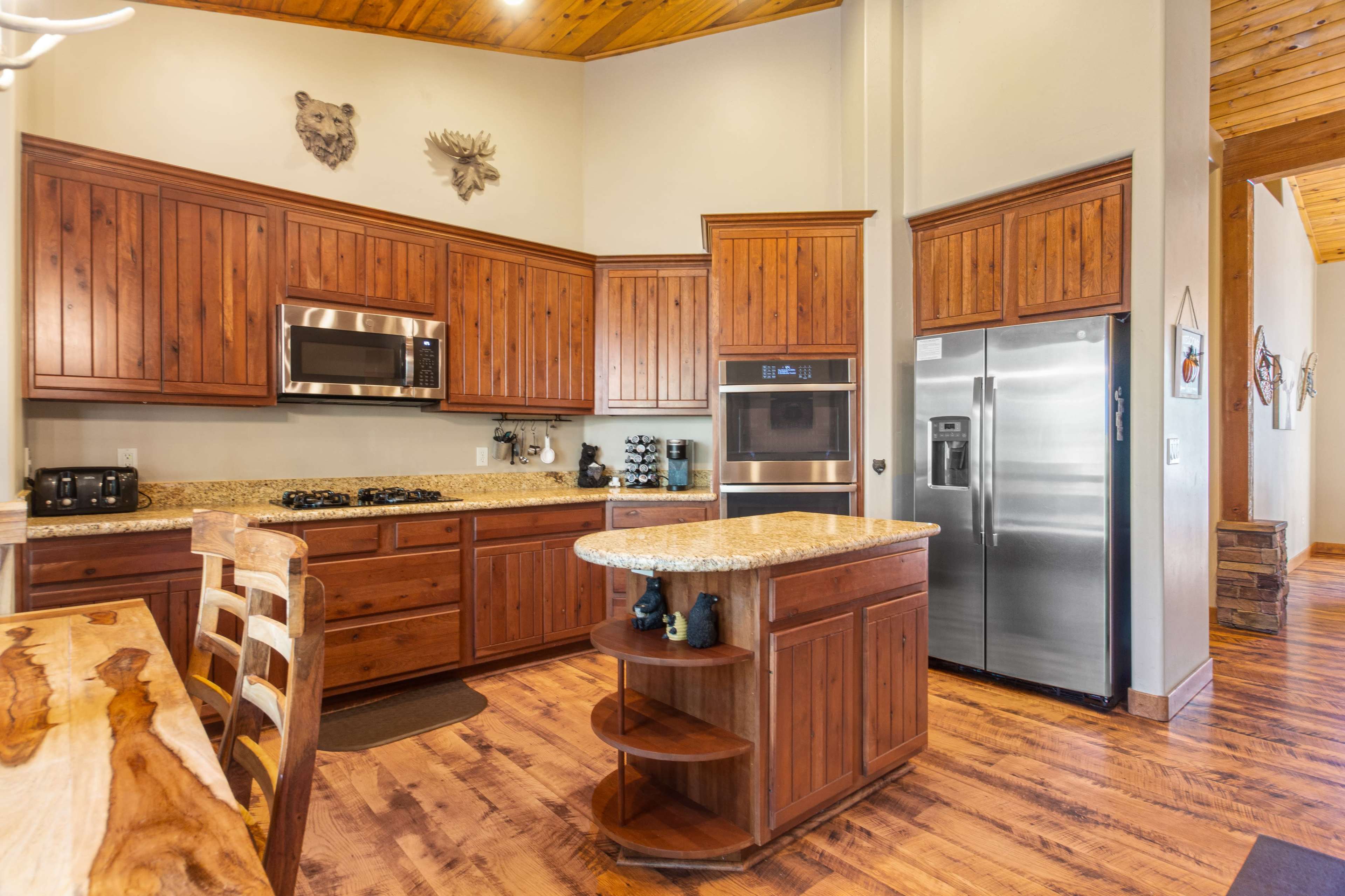 The kitchen features wooden cabinetry, granite countertops, stainless steel appliances, and a central island with a built-in shelf.