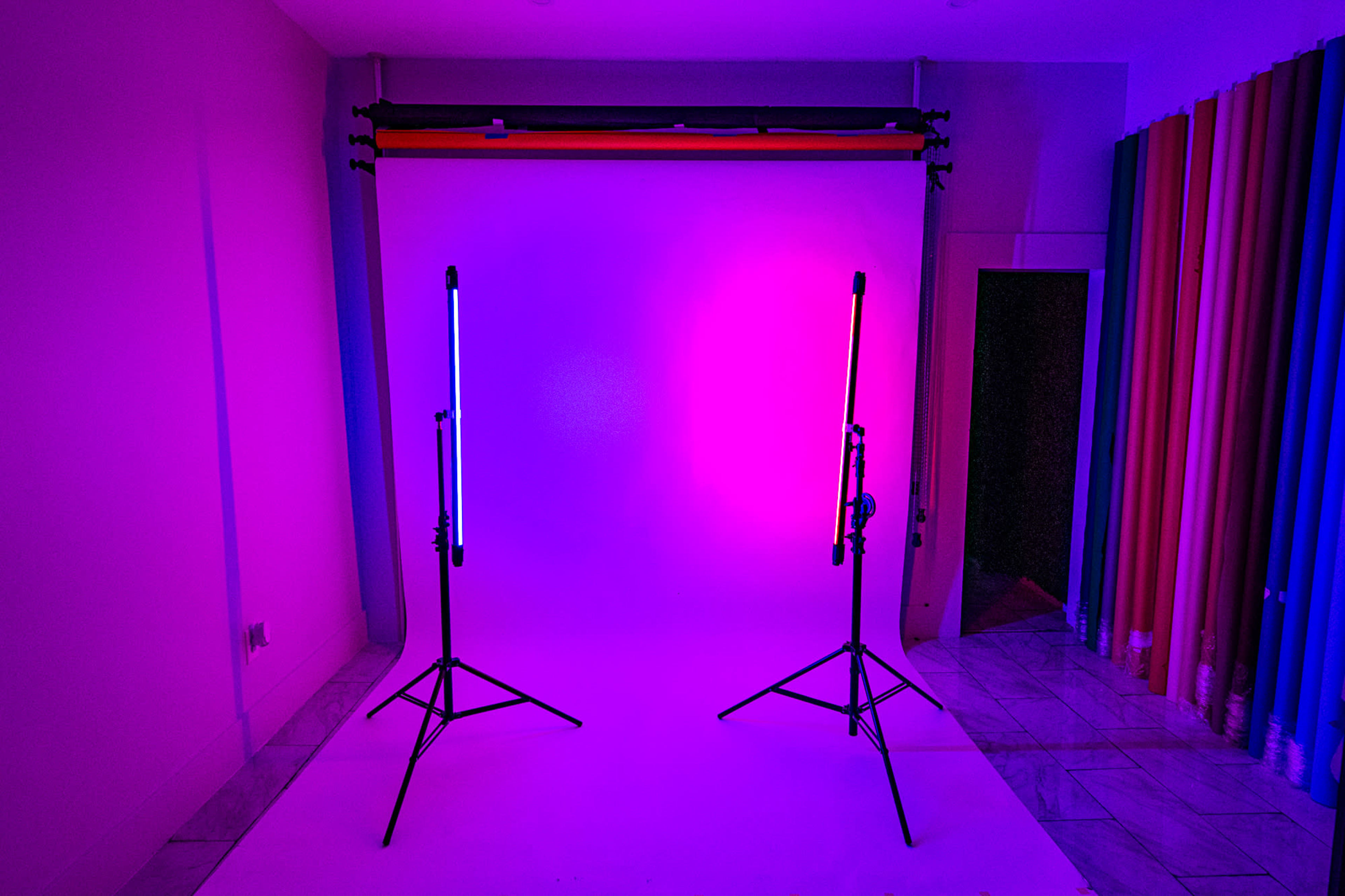 A photography studio with two illuminated light stands positioned in front of a colorful backdrop.