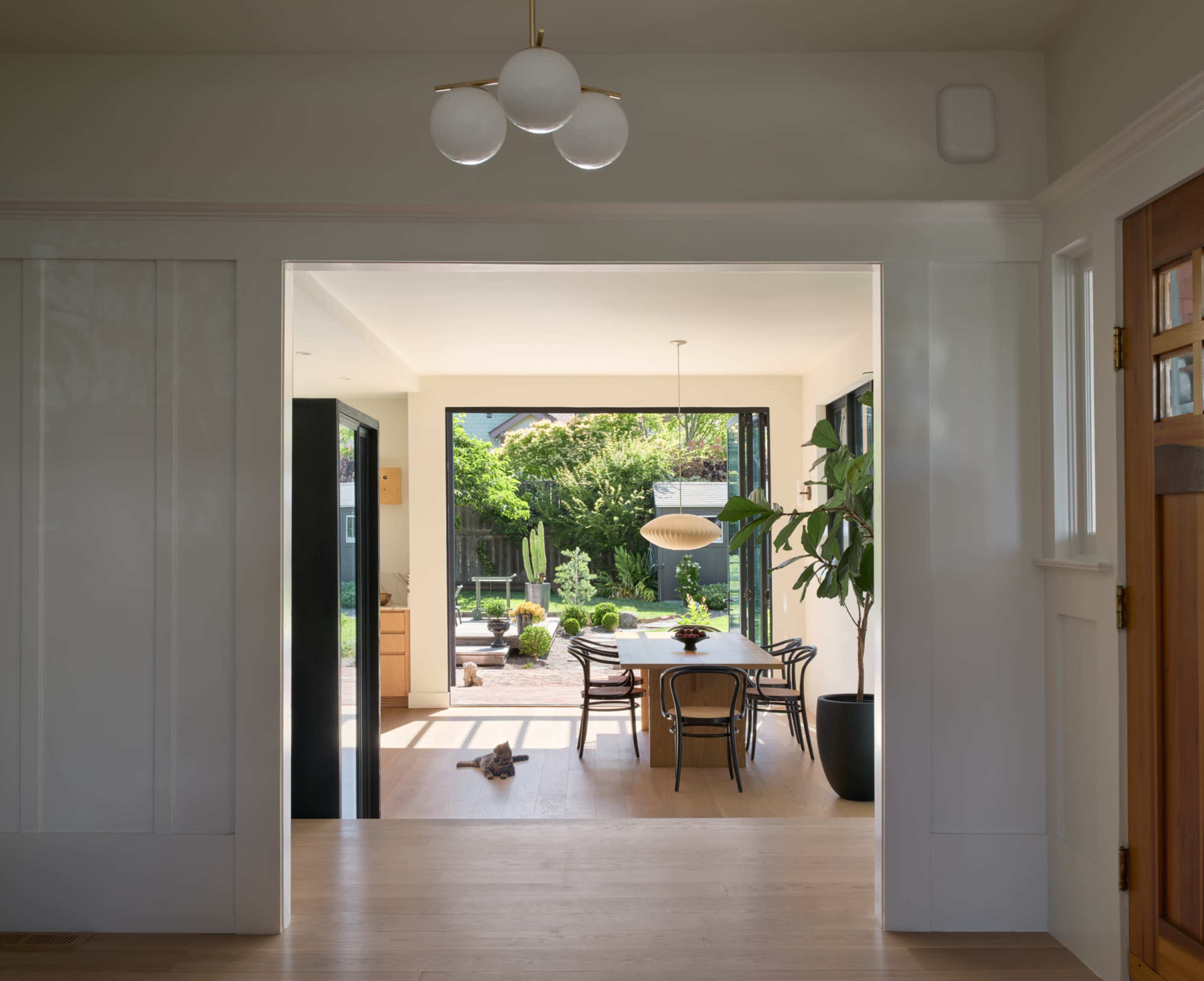 A bright, modern entryway leads to a dining area that opens up to a garden patio.